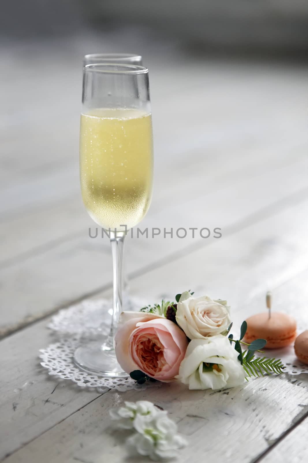 Two glasses with champagne, boutonniere with roses and cookies