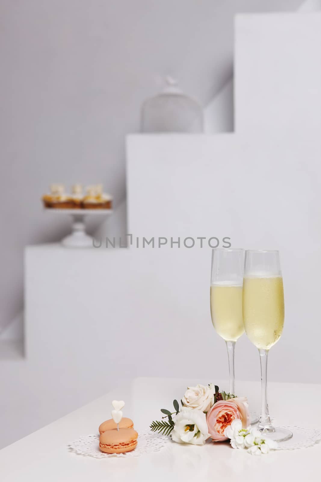 Two glasses with champagne, boutonniere with roses and cookies