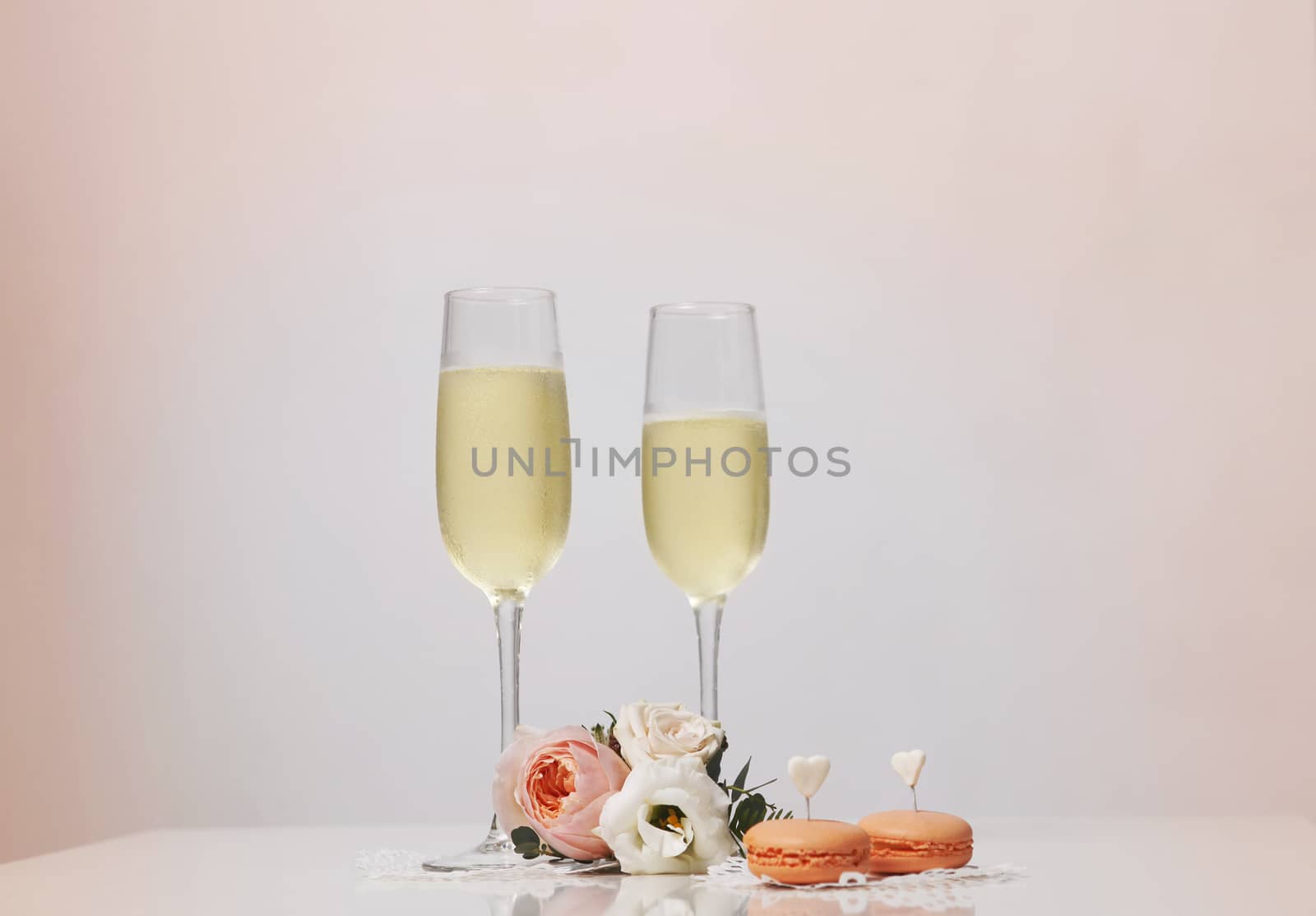 Two glasses with champagne, boutonniere with roses and cookies