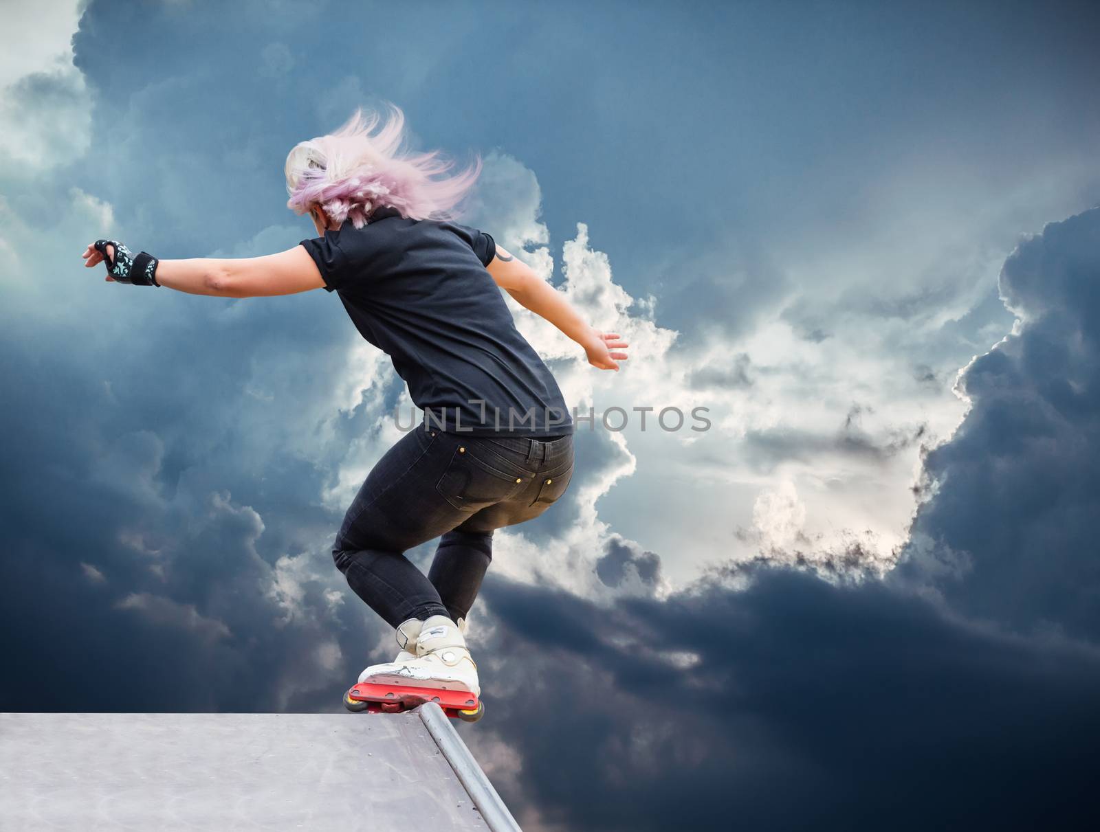 girl roller performs a trick against the sky