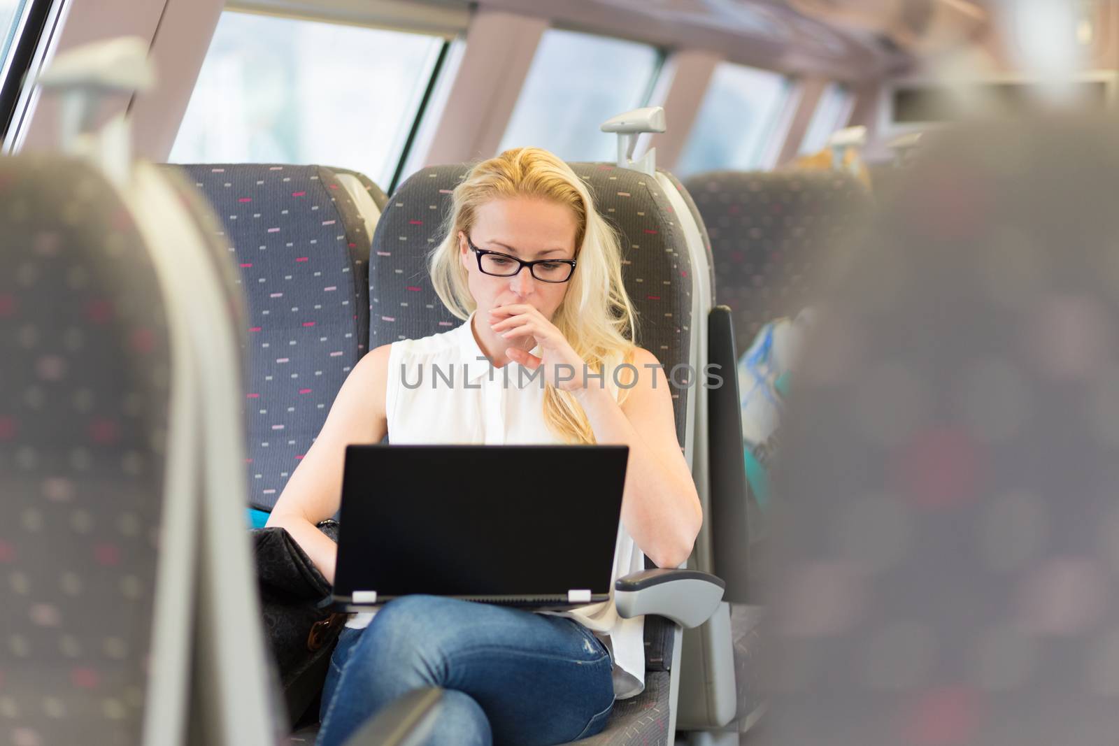 Businesswoman sitting and traveling by train working on laptop.