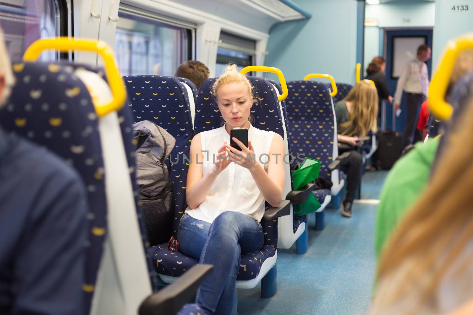 Woman using mobile phone while travelling by train. by kasto