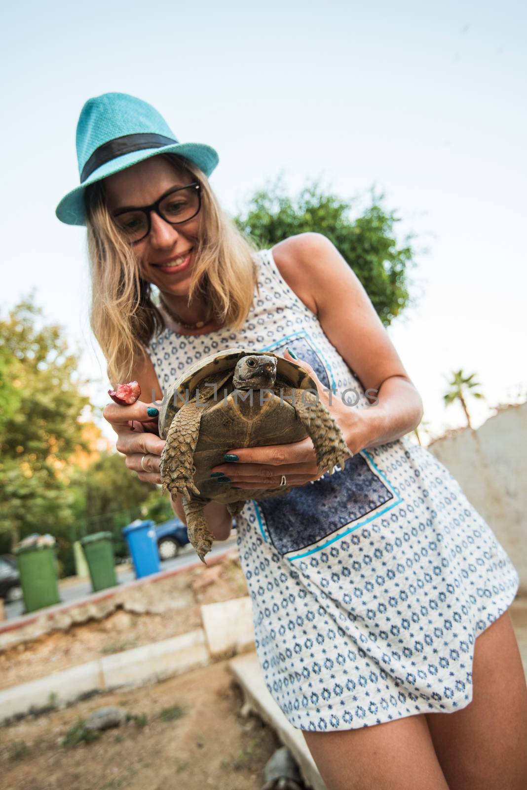 Happy young woman feeding turtle with cherry