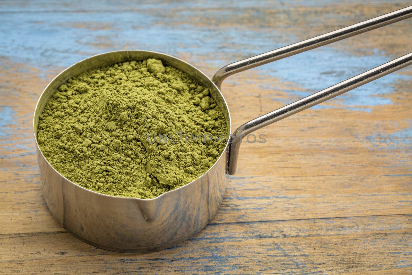 measuring scoop of organic matcha green tea powder against grunge wood