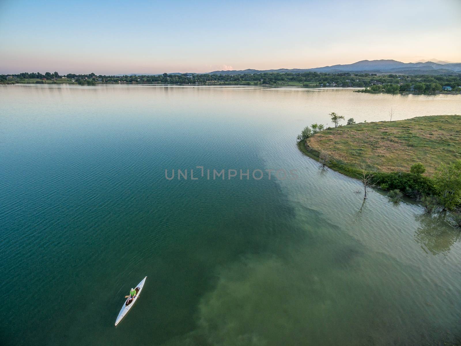 aerial view of a lake with canoe, summer evening in Colorado with Rocky Mountains in background