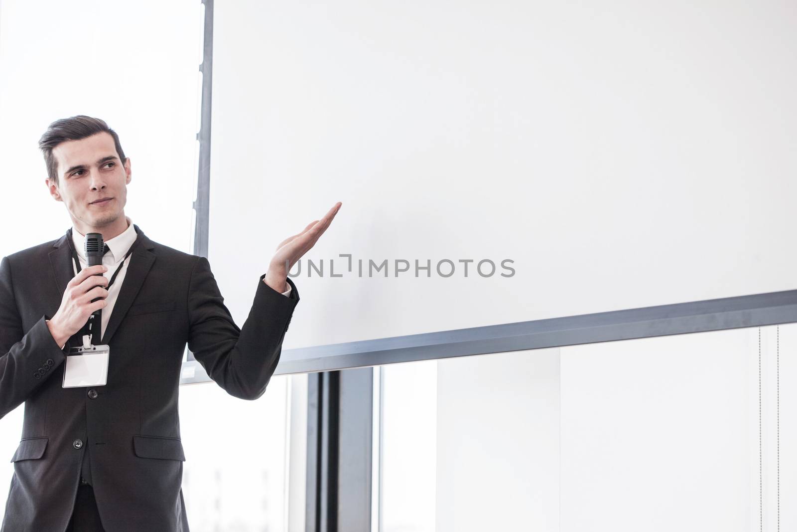 Business man speaking at presentation in microphone in office