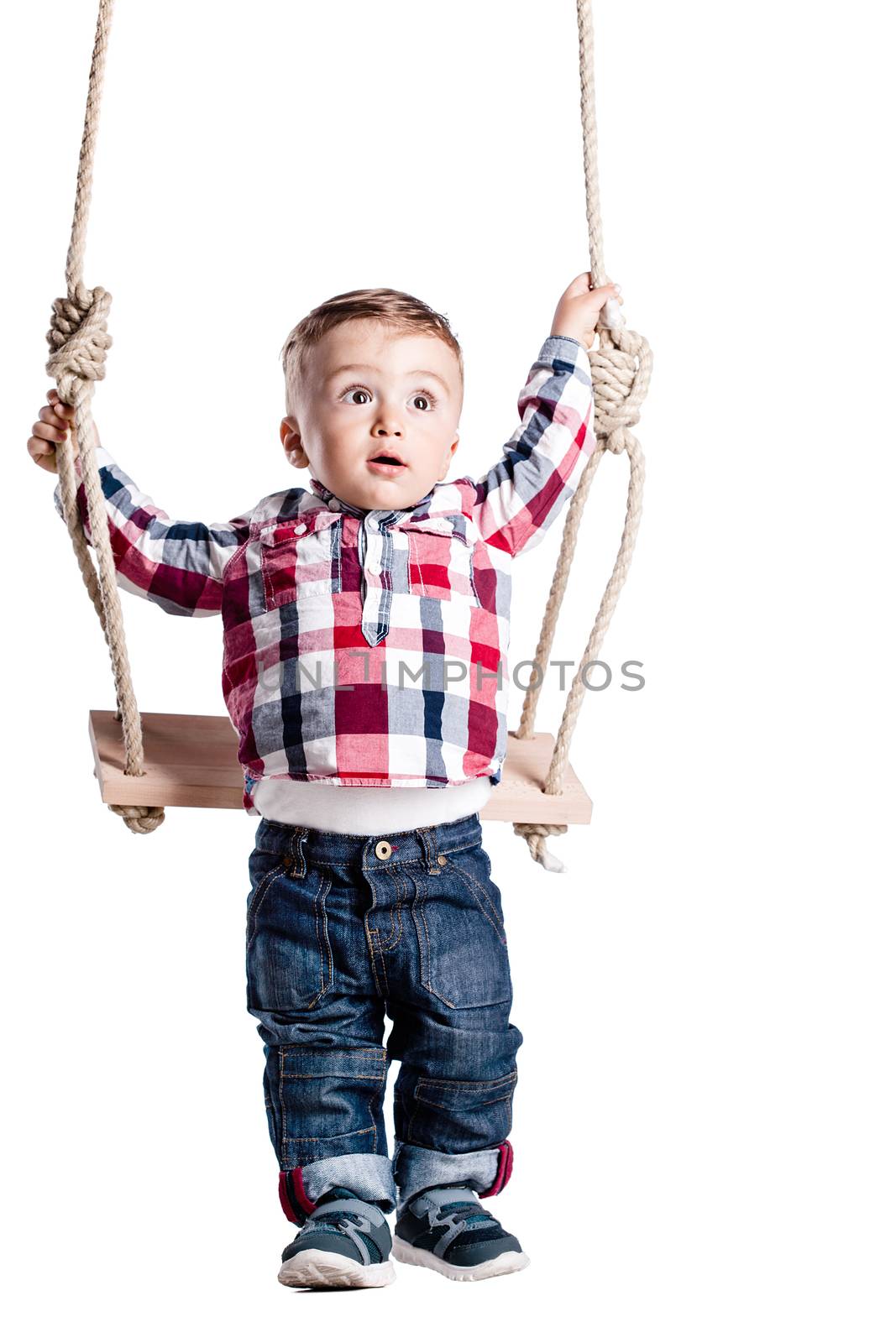 happy little boy swinging on a wooden swing