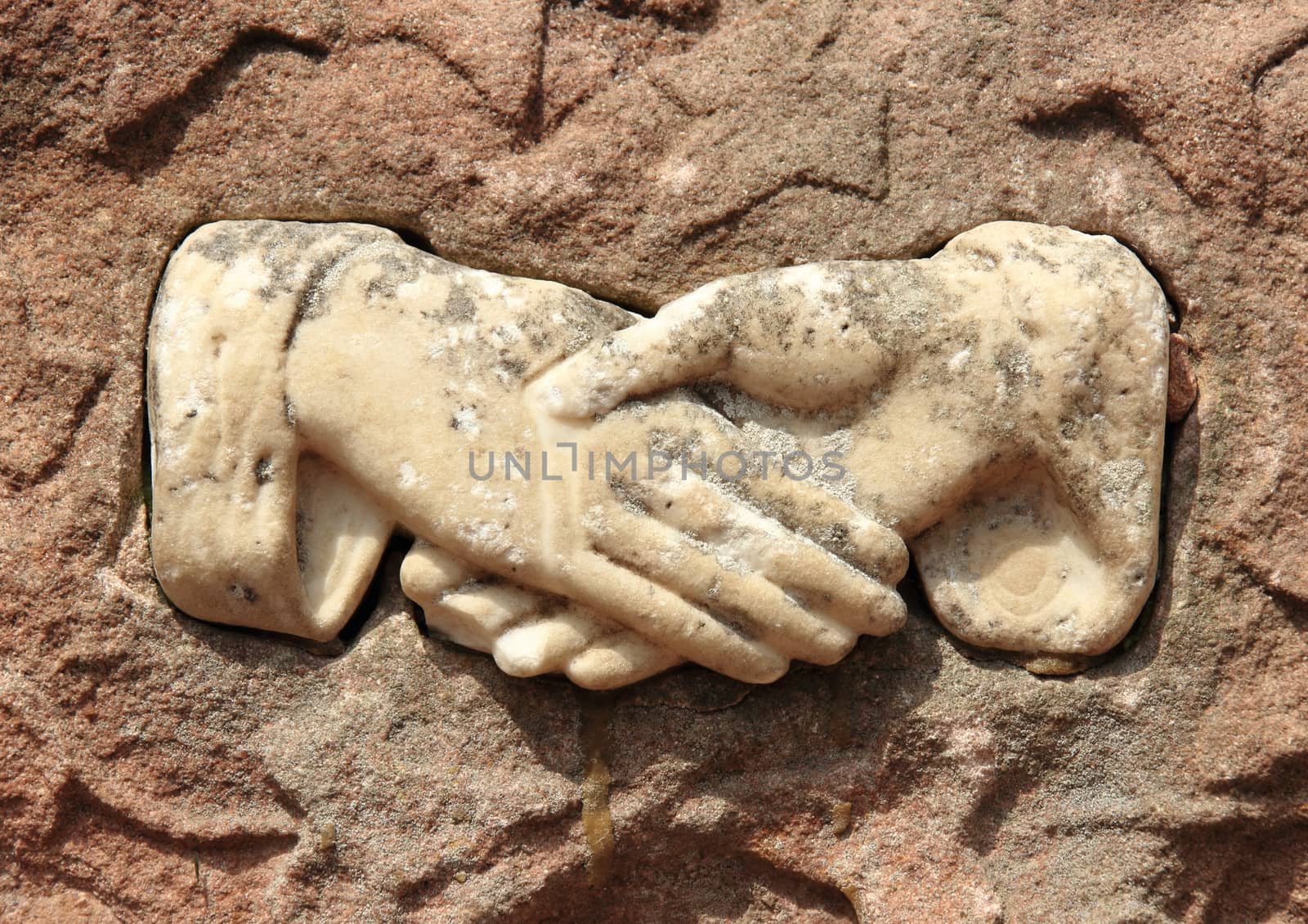 Old effigy of shaking hands in marble
