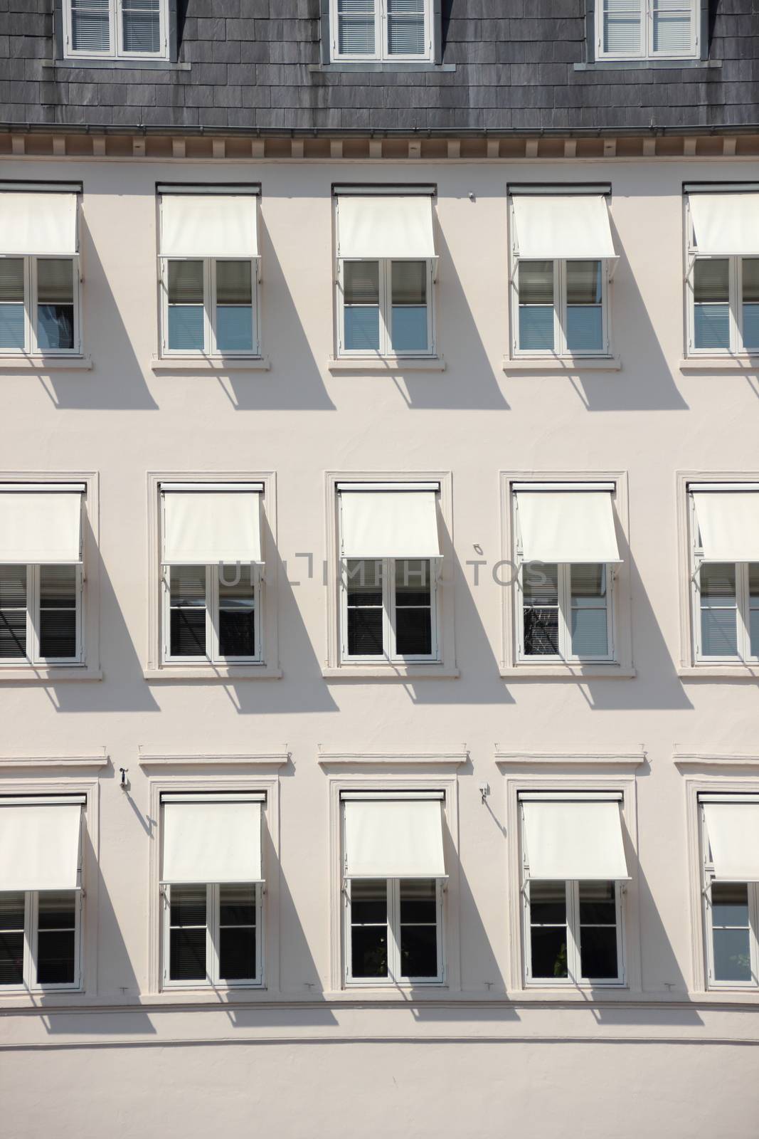 Facade of grey building with  white awning and shade by HoleInTheBox