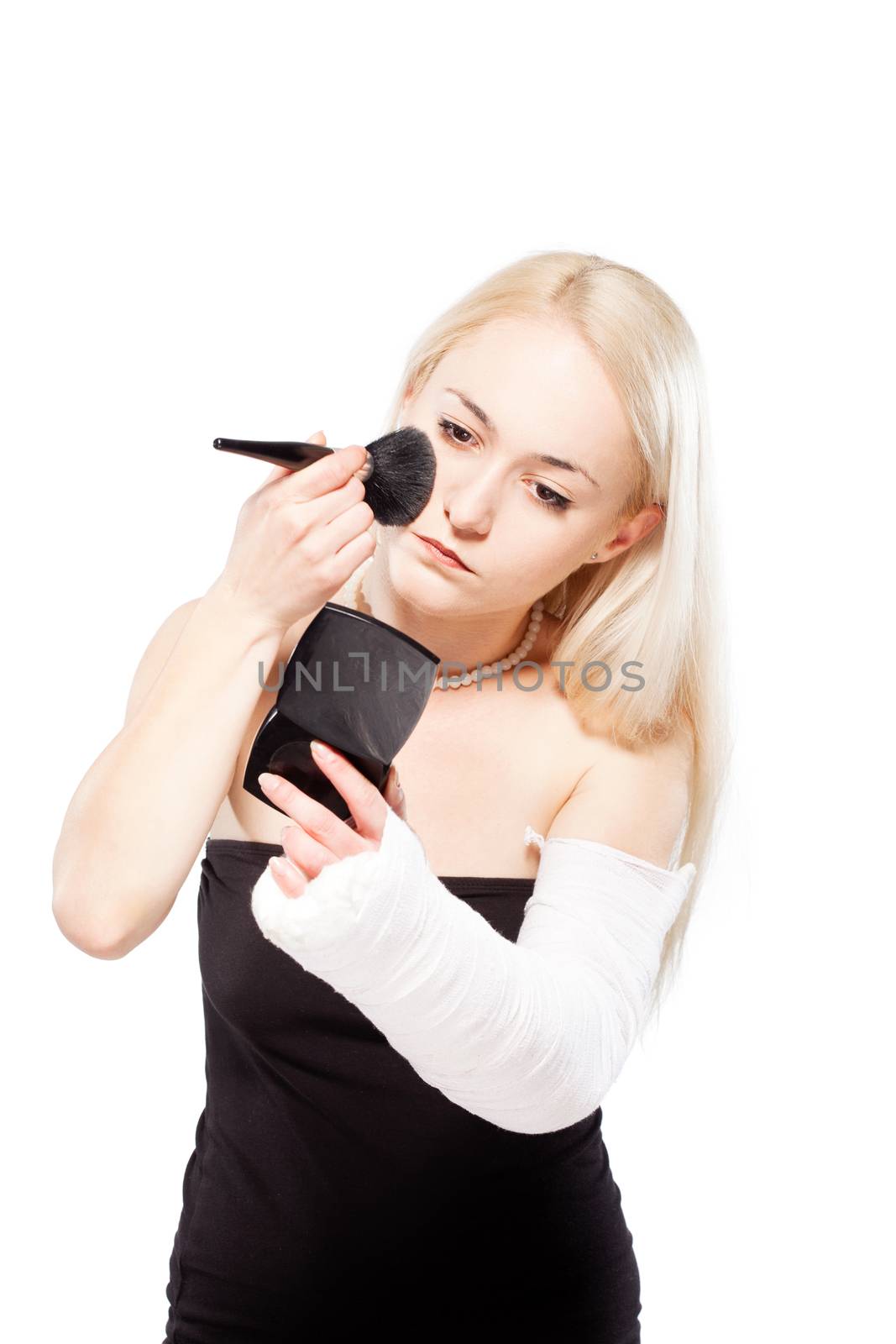 Blond girl with a broken arm in plaster having trouble putting a lipstick
