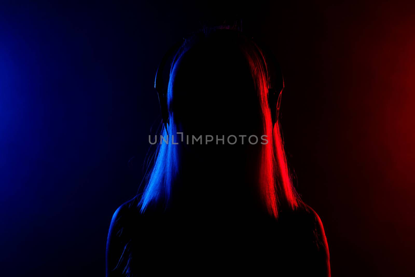 silhouette of a girl with headphones, red and blue lights in the background