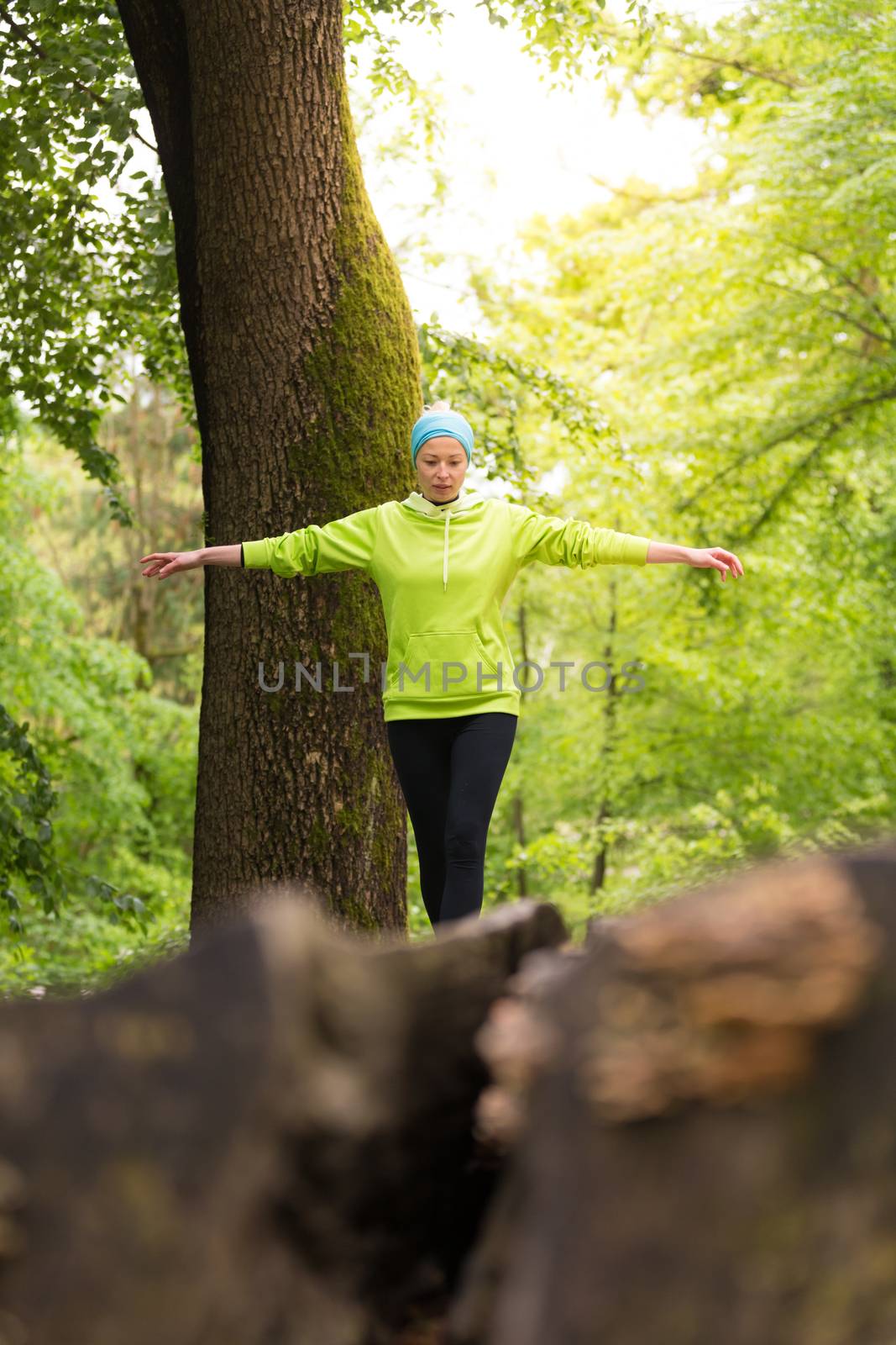 Woman holding balance on tree trunk in nature. by kasto