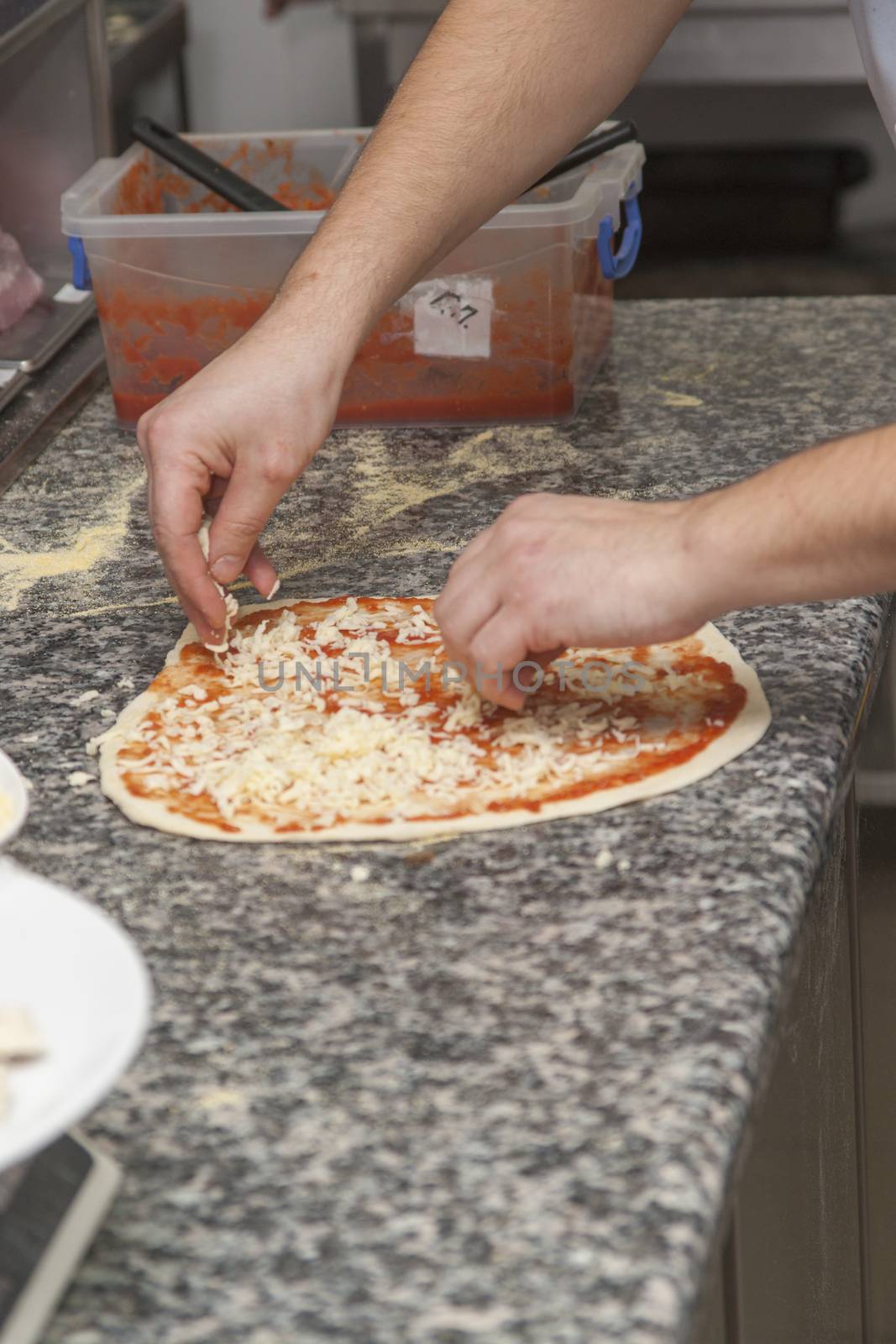 Man chef with raw pizza. Young male in uniform preparing pizza on table.