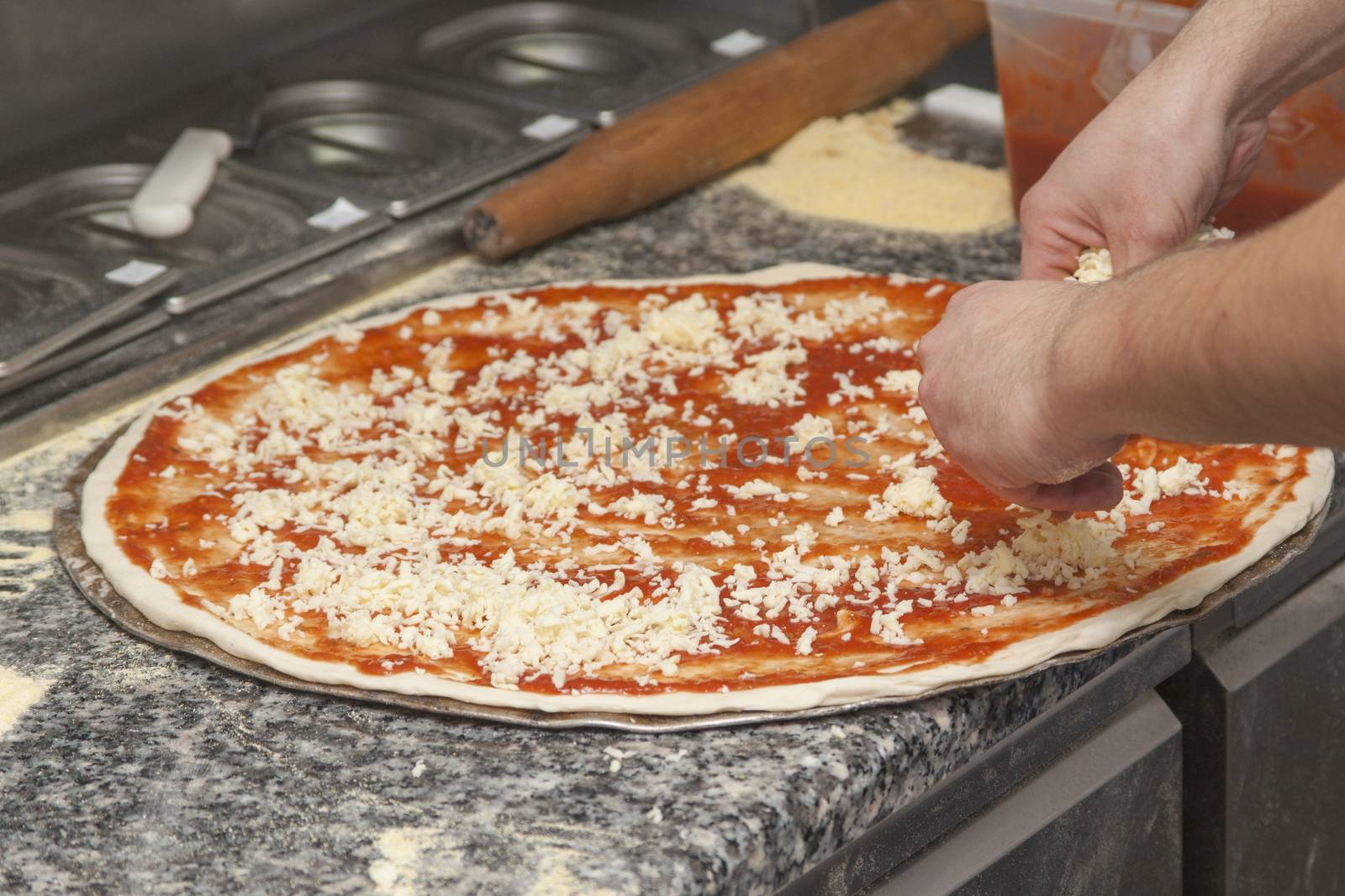 Man chef with raw pizza. Young male in uniform preparing pizza on table.