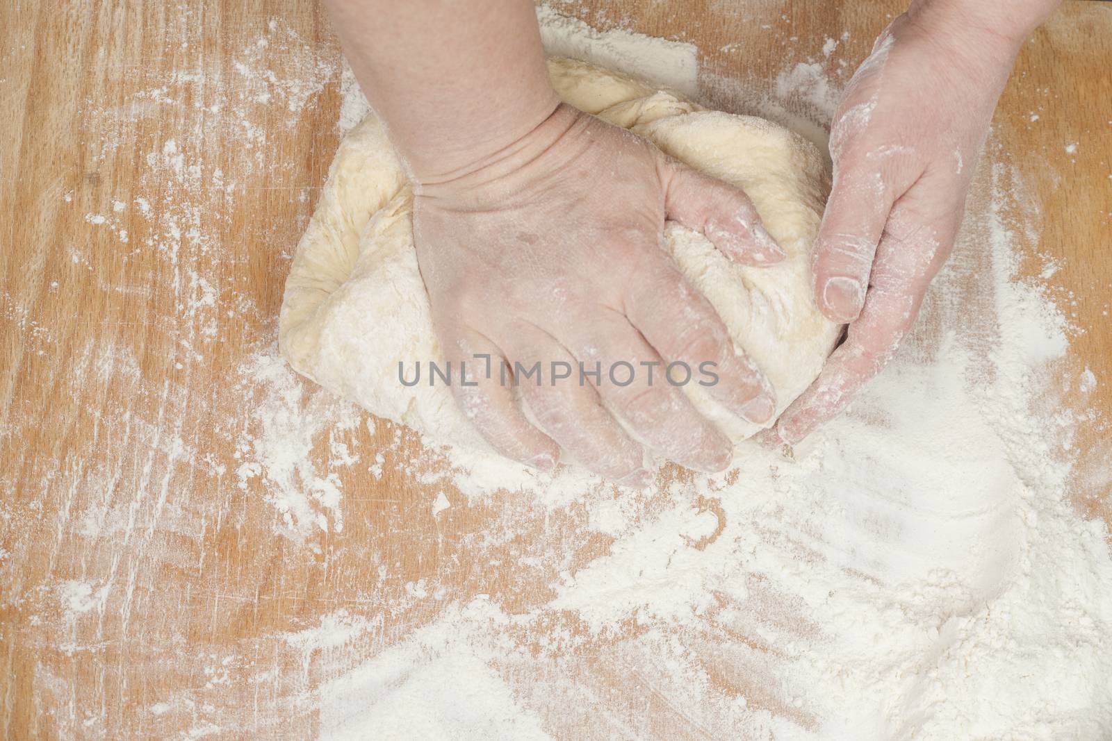 Women's hands preparing fresh yeast dough on wooden table