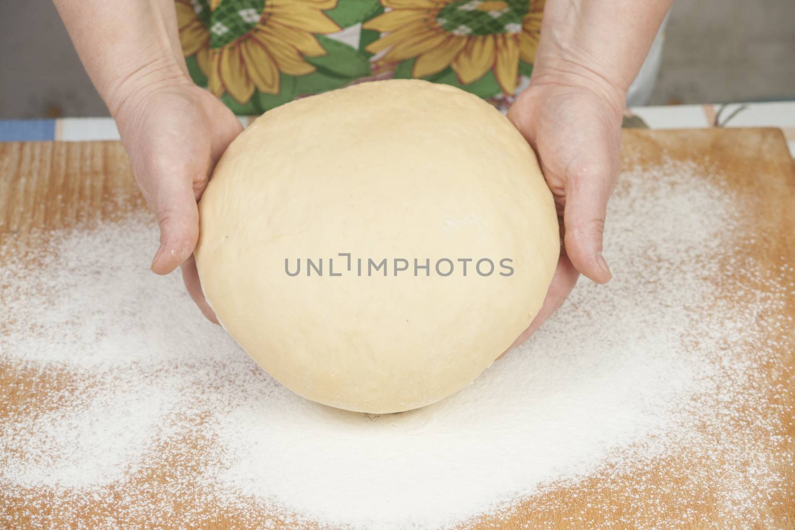 Ball of pizza dough with flour on the wooden table