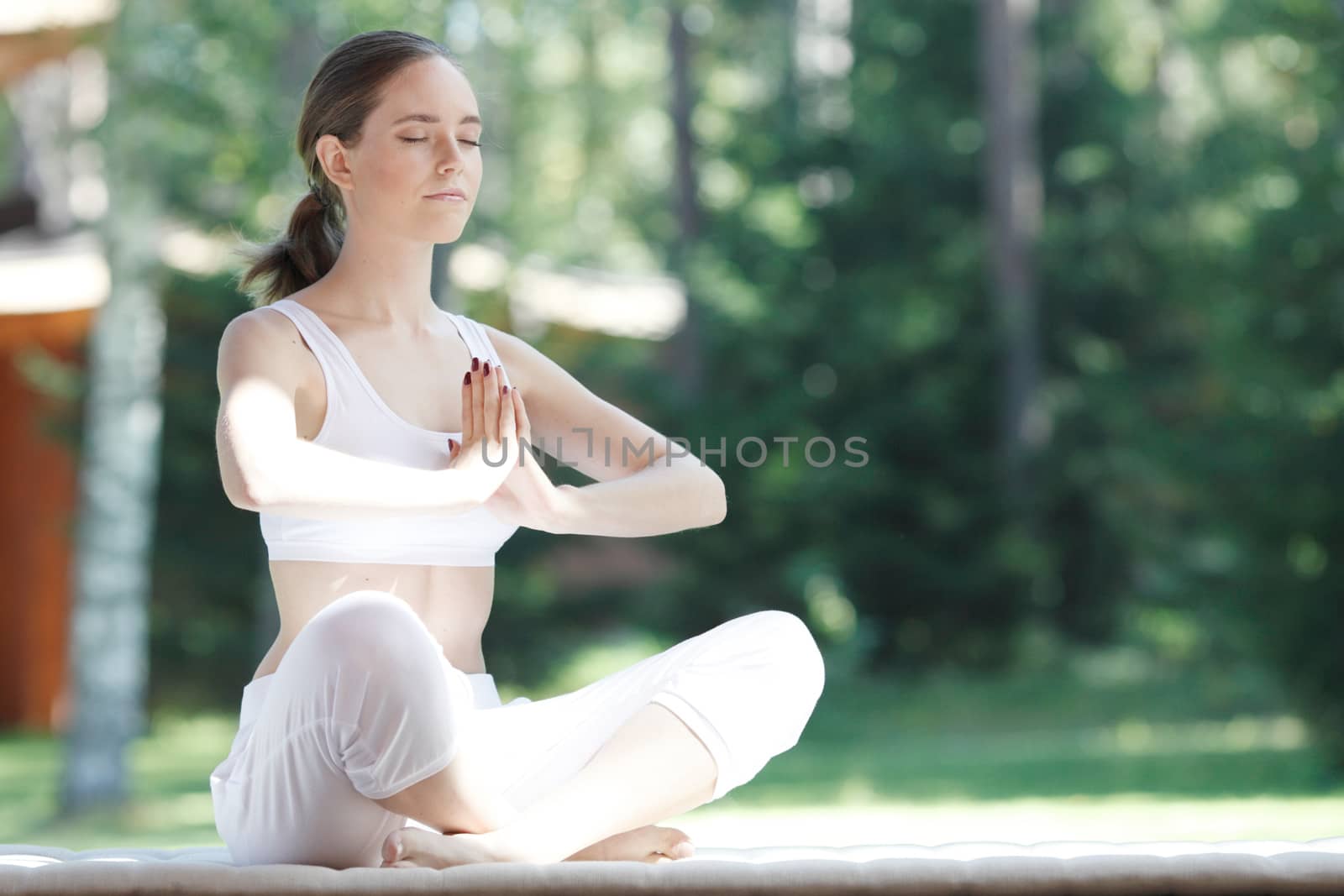 Young woman doing yoga lotus exercise outdoors