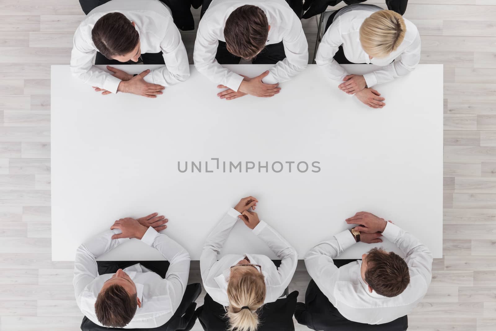 Business team sitting around white table, white copy space