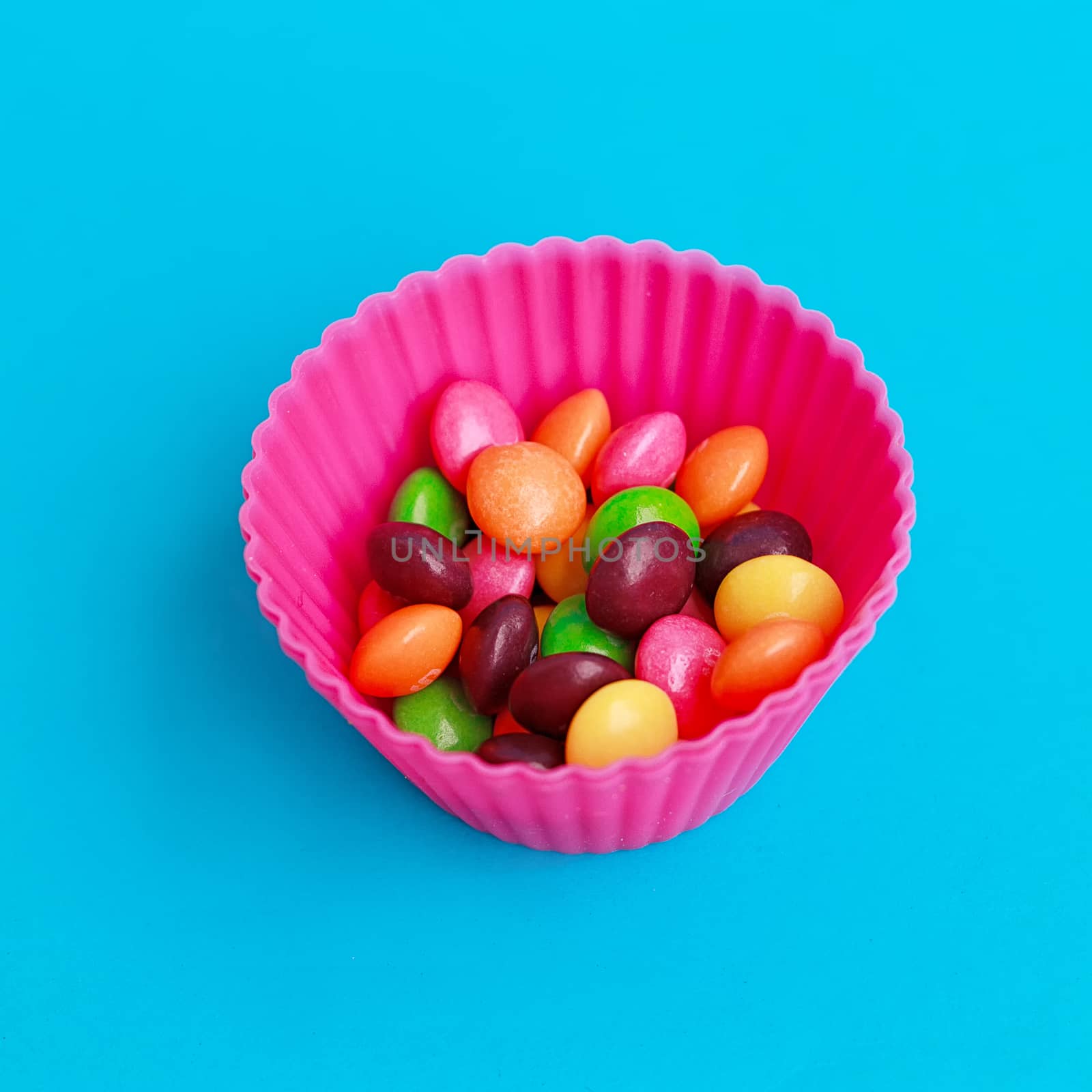 Colorful candies in cupcake case on the blue background