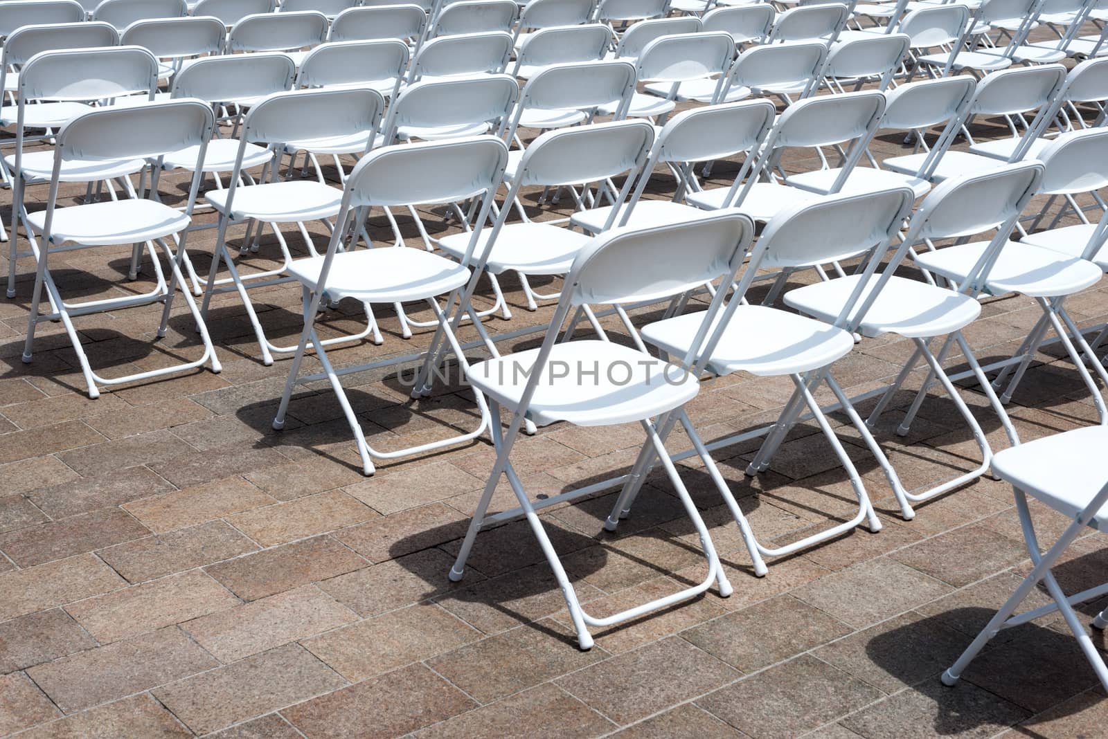 rows of folding chairs at event by DNKSTUDIO