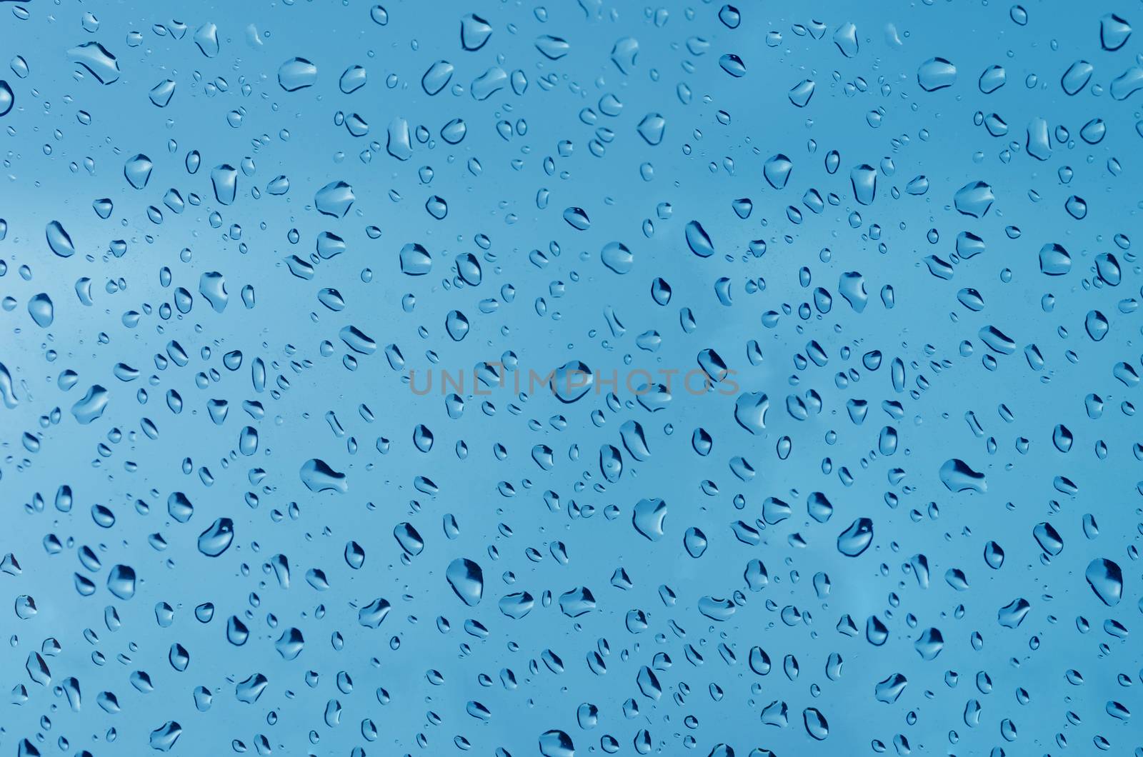 Water droplets on the glass with a colored background. Drops of water.