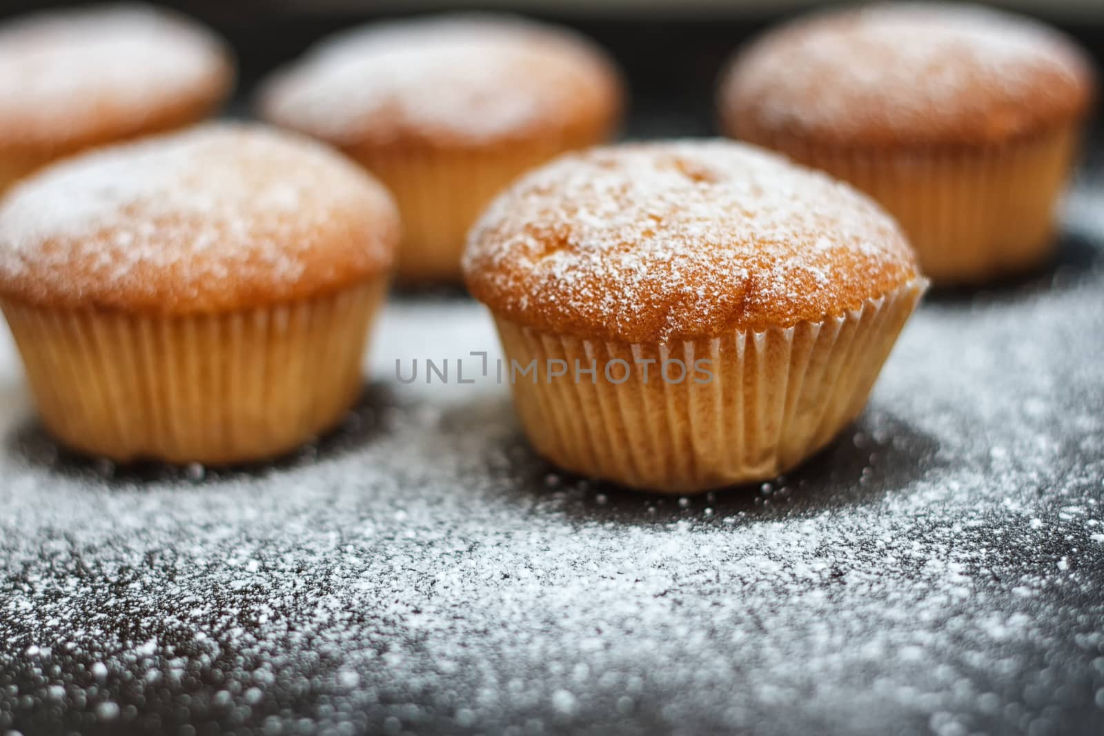 muffins in powdered sugar on a dark table