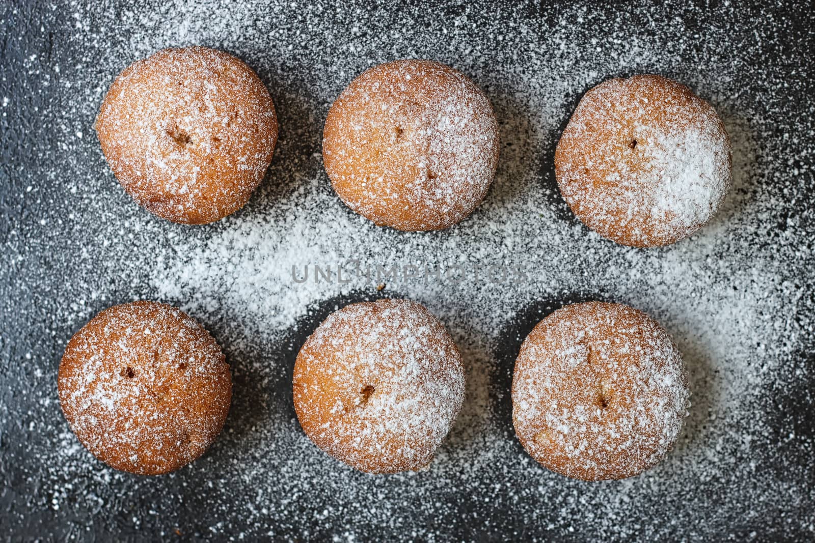muffins in powdered sugar on a dark table