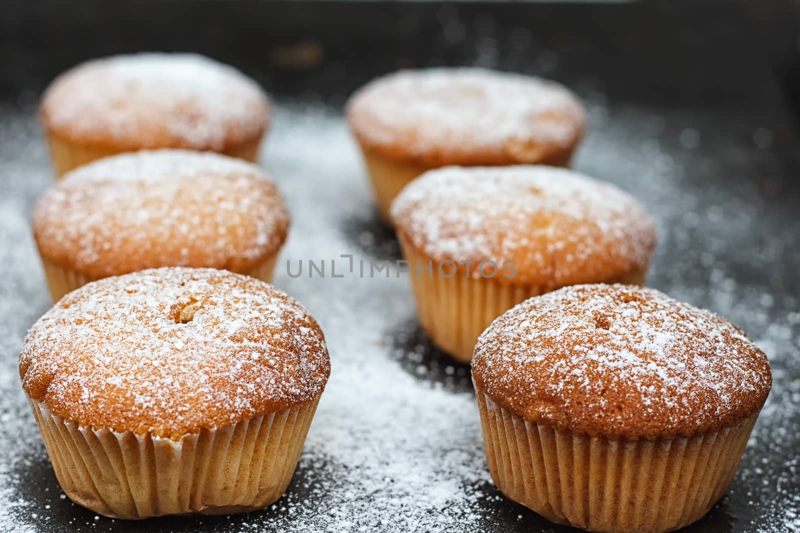 muffins in powdered sugar on a dark table