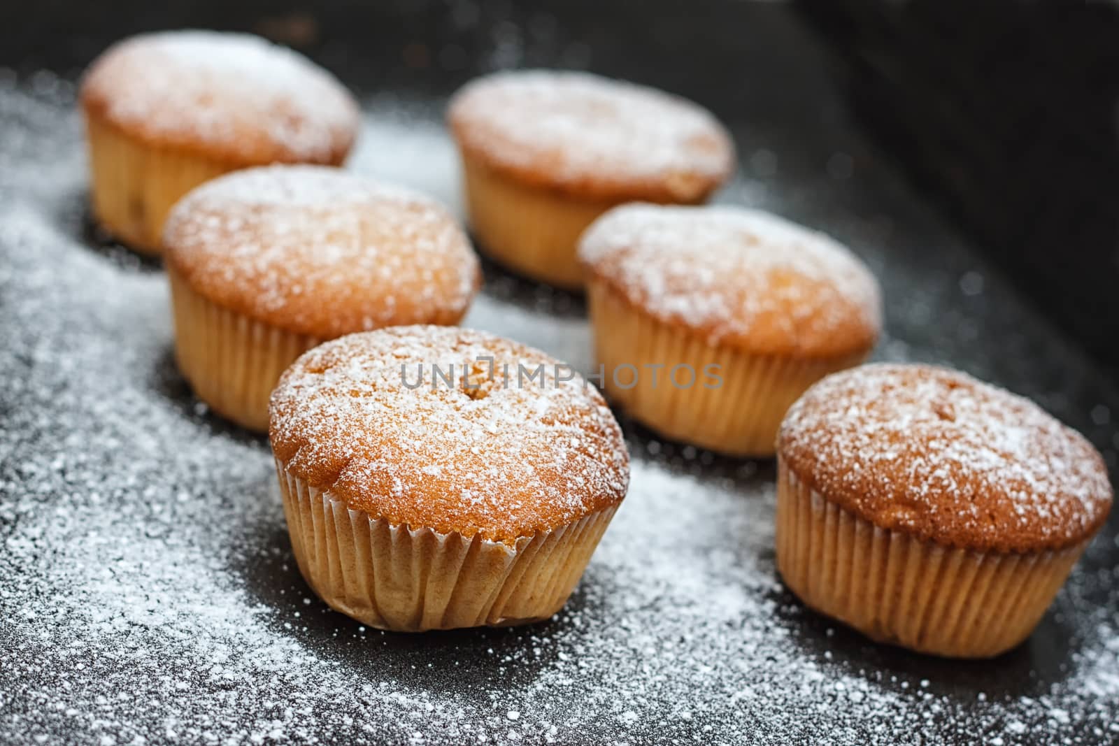 muffins in powdered sugar on a dark table
