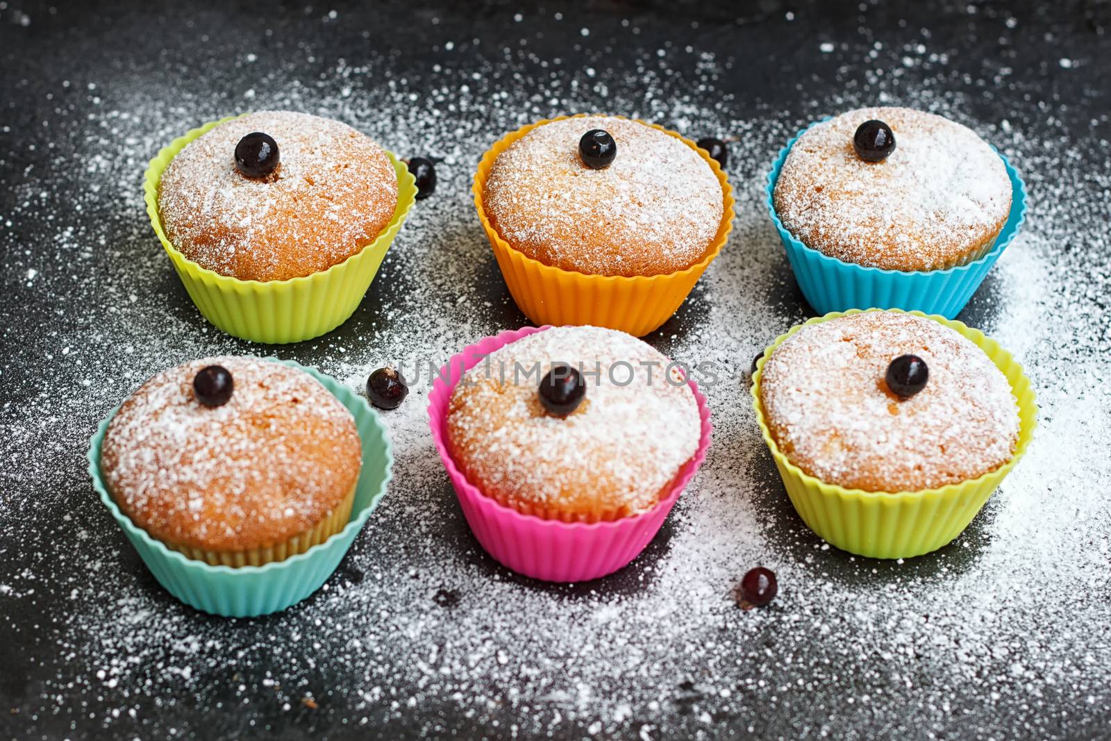 Muffins with black currant in silicone forms sprinkled with powdered sugar