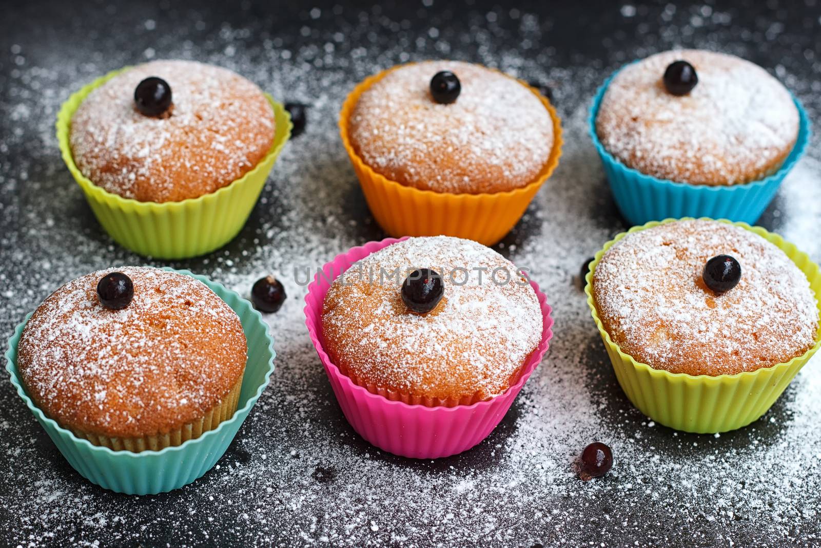 Muffins with black currant in silicone forms sprinkled with powdered sugar