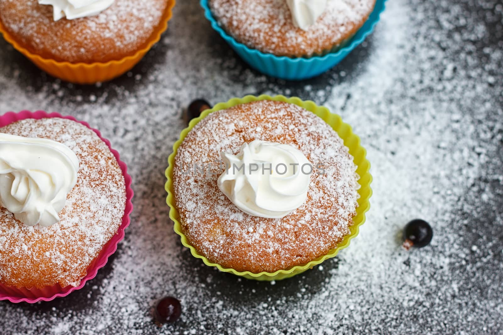 Muffins in colorful silicone forms with whipped cream