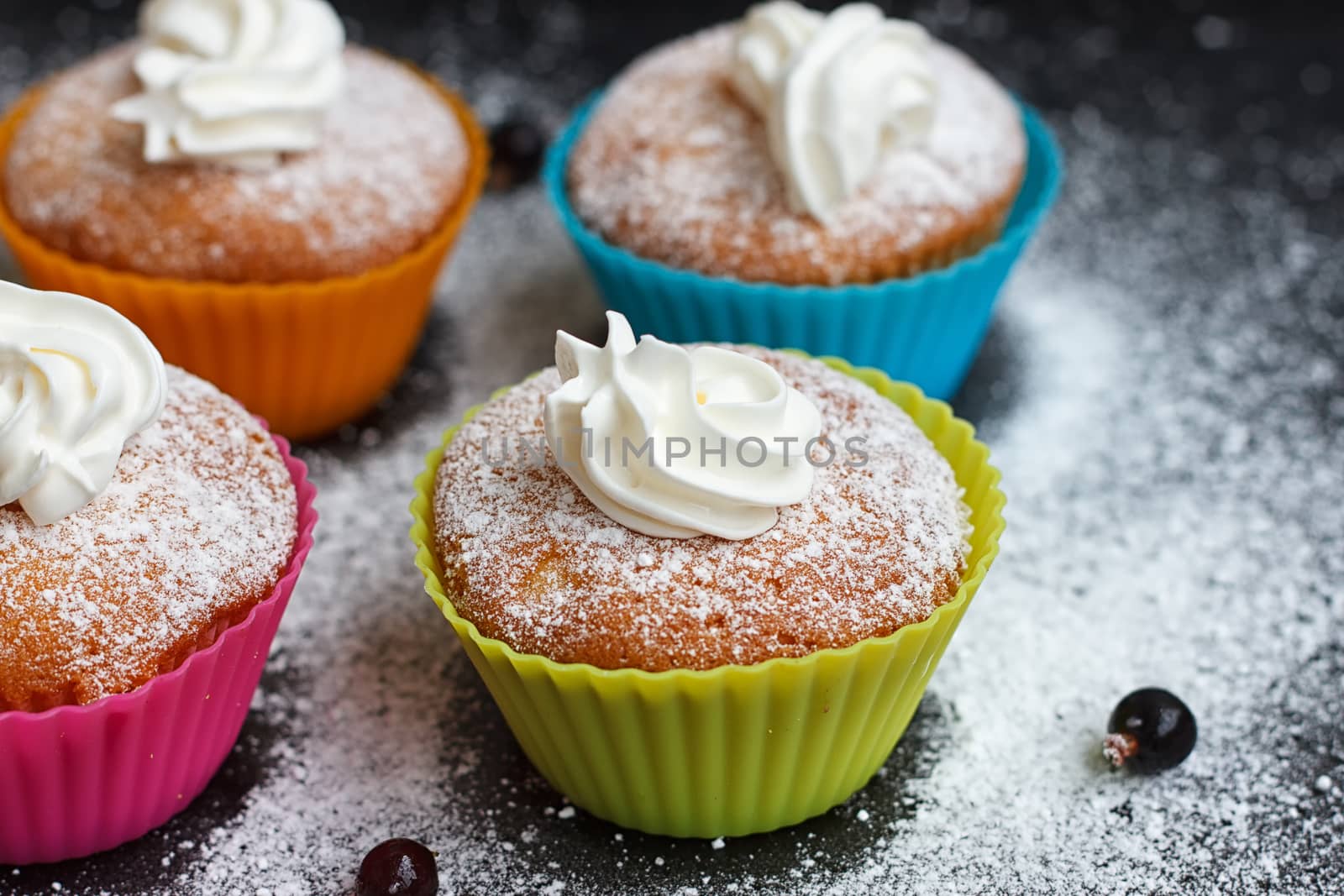 Muffins in colorful silicone forms with whipped cream