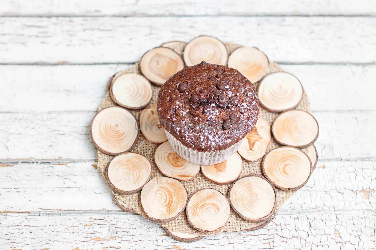 Chocolate muffin on a wooden stand on a light background