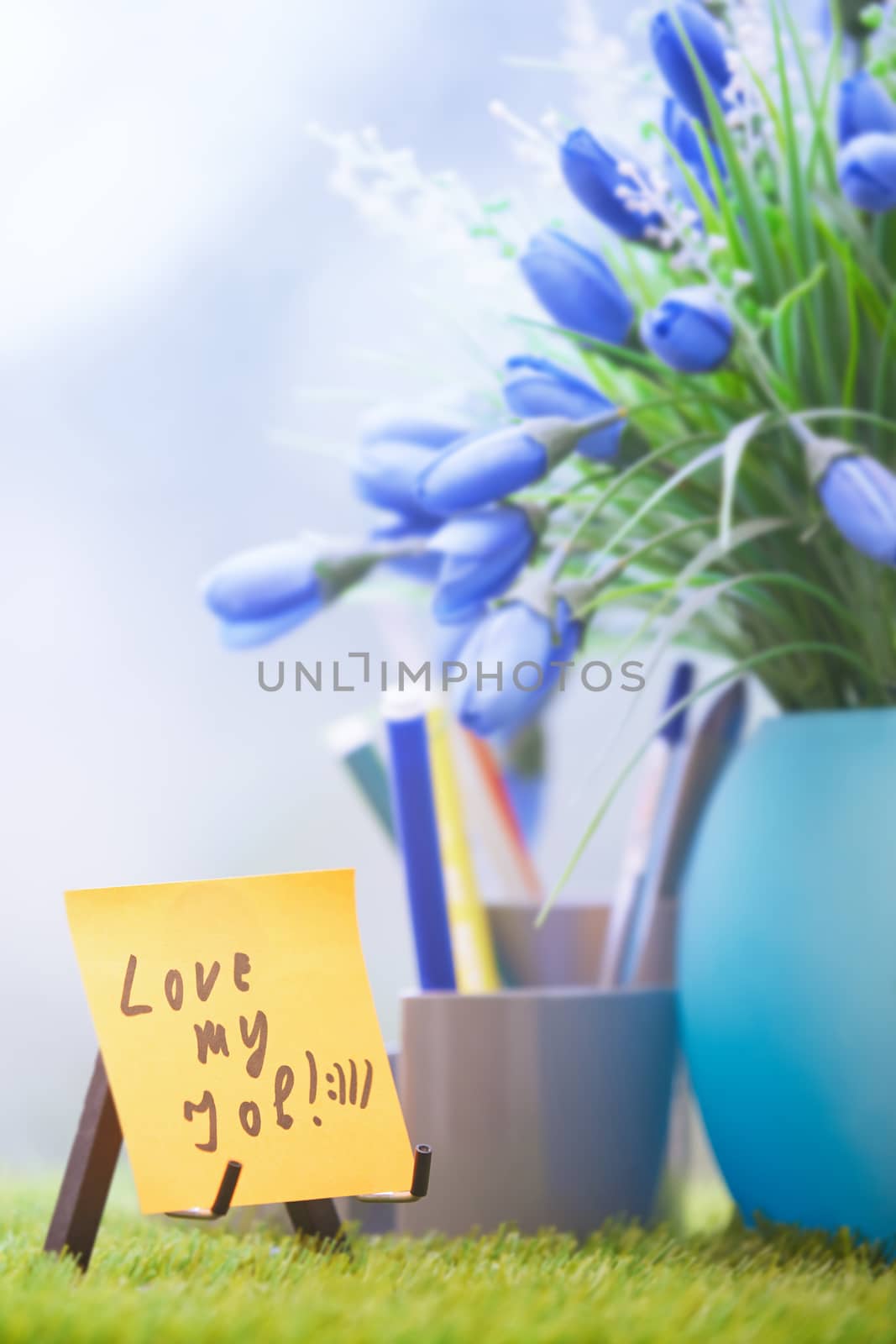 Adhesive note with Love my job text at green office by Novic