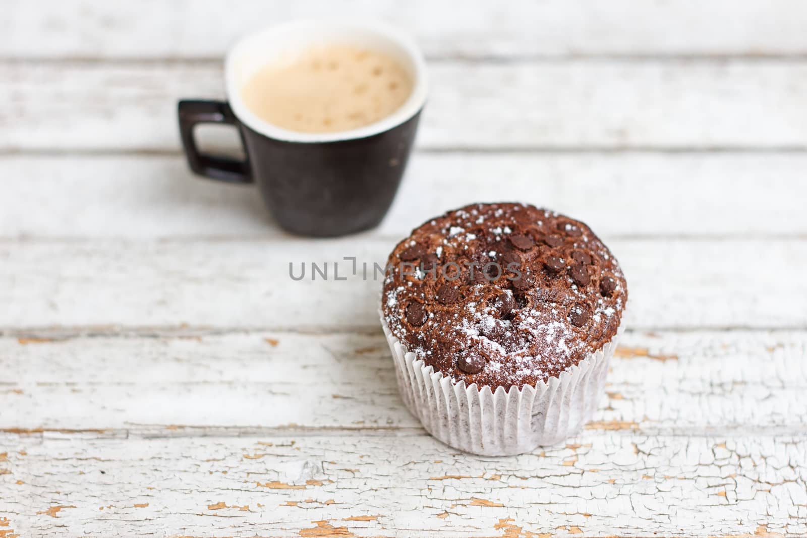 chocolate muffin and cup of coffee on the white wooden background