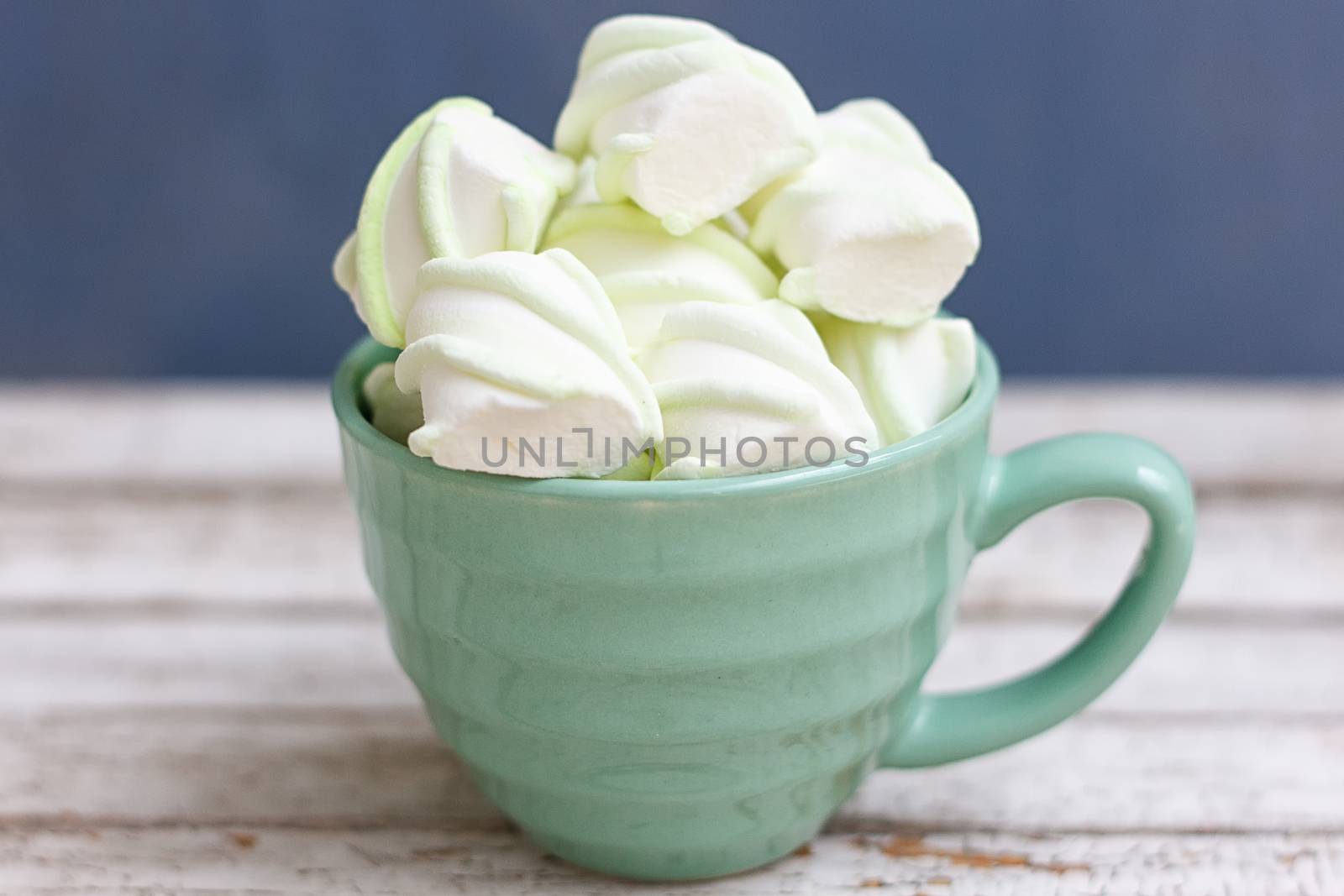 Peppermint large marshmallows in a large green cup on a blue background