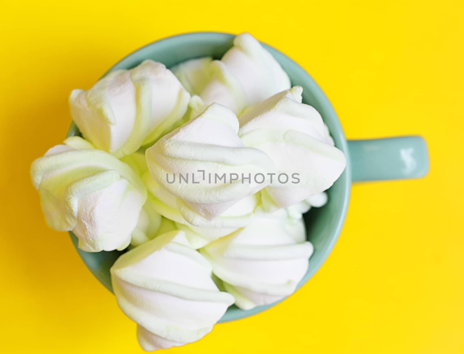 Peppermint large marshmallows in a large green cup on a yellow background