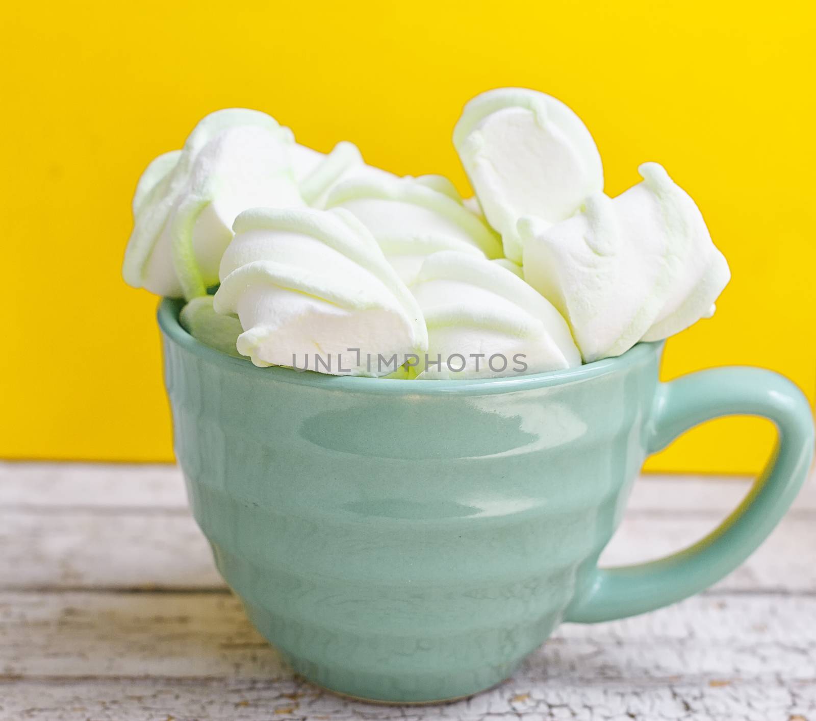 Peppermint large marshmallows in a large green cup on a yellow background