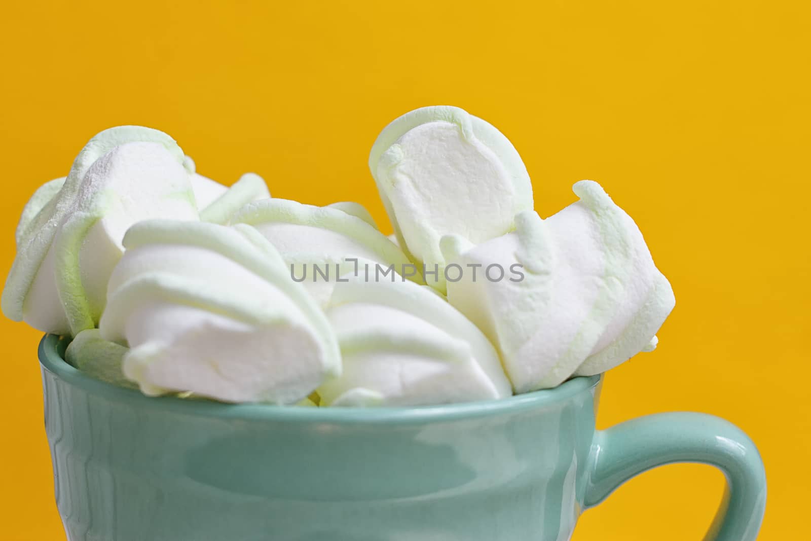 Peppermint large marshmallows in a large green cup on a yellow background