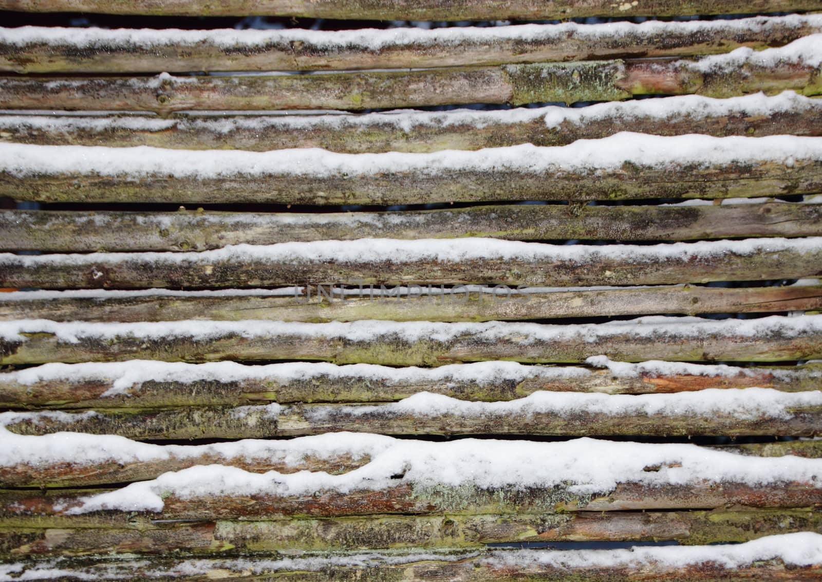 Snowy wooden pole fence wall in winter