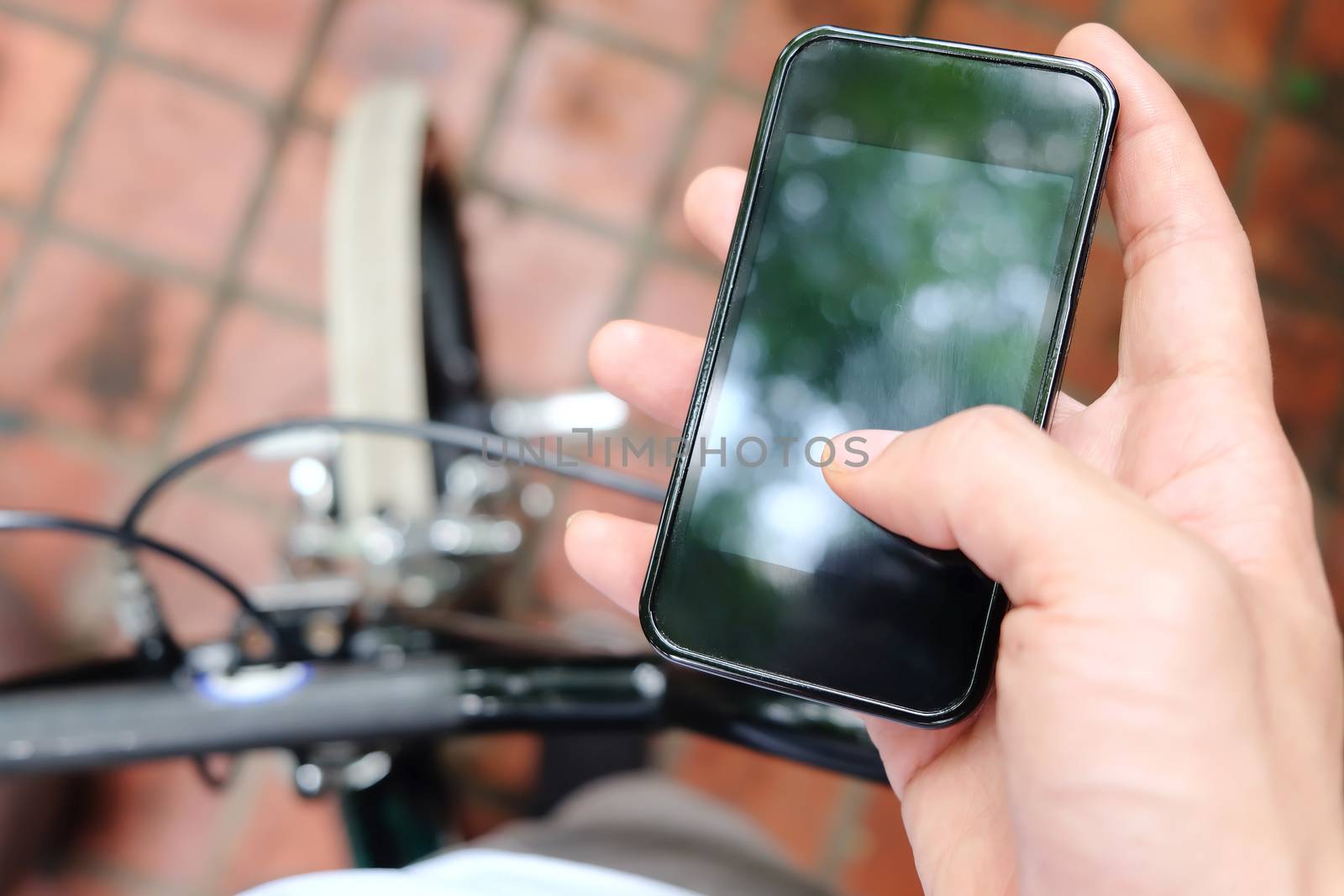 Close up image of man hand with bicycle texting on mobile phone
