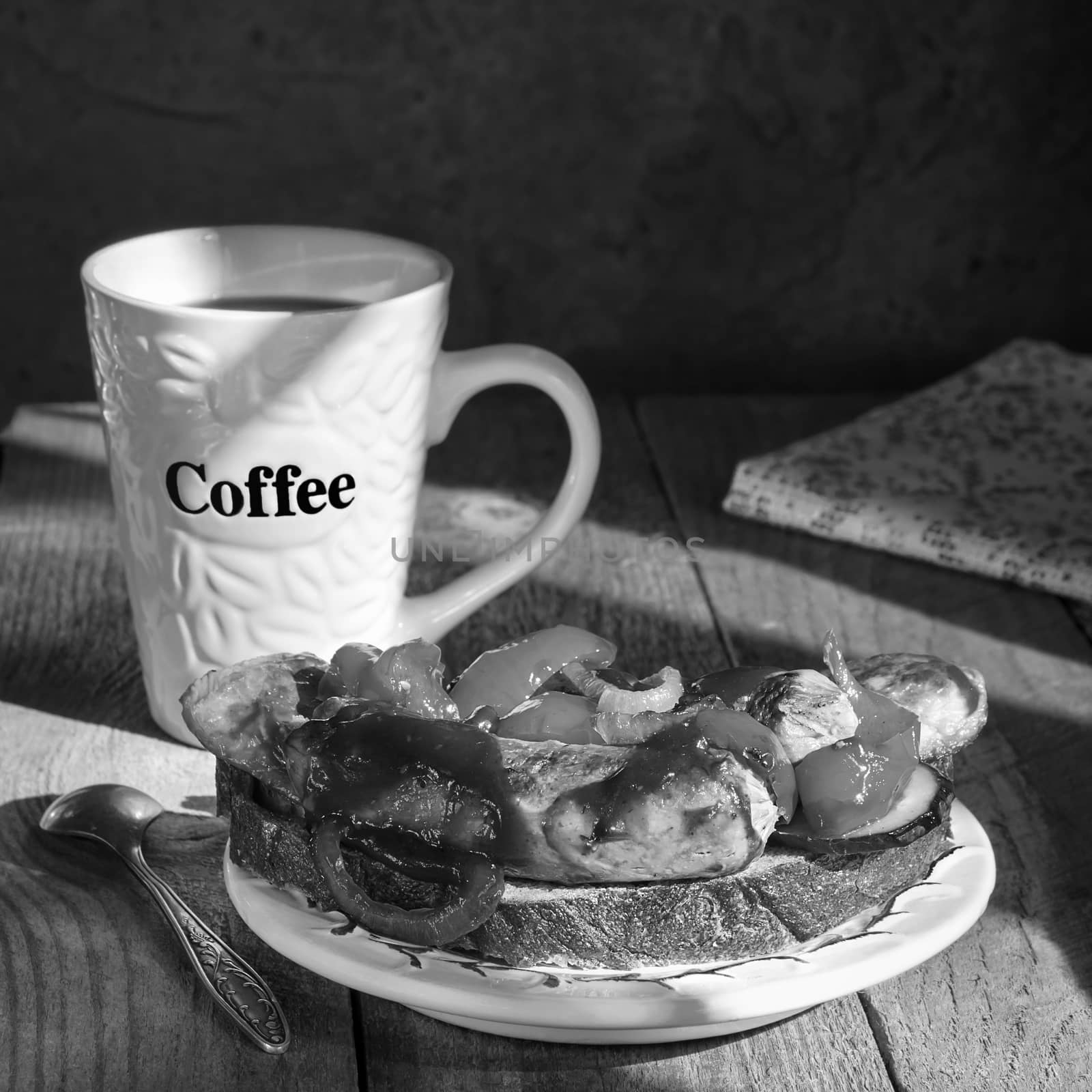 Sandwich with grilled sausages, on a plate and coffee mug on old wooden surface. Black-and-white.