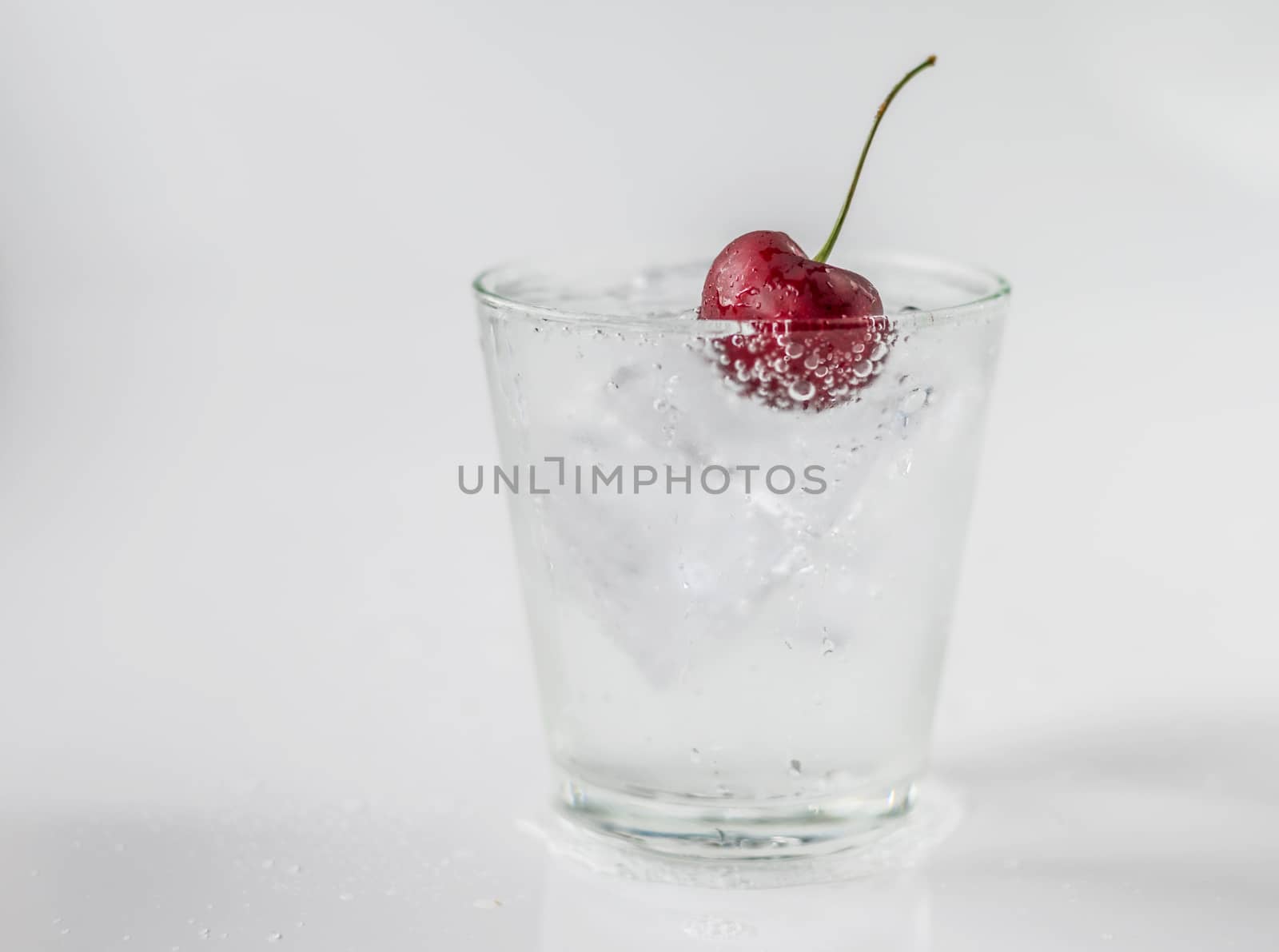 Cherry in glass of soda and ice