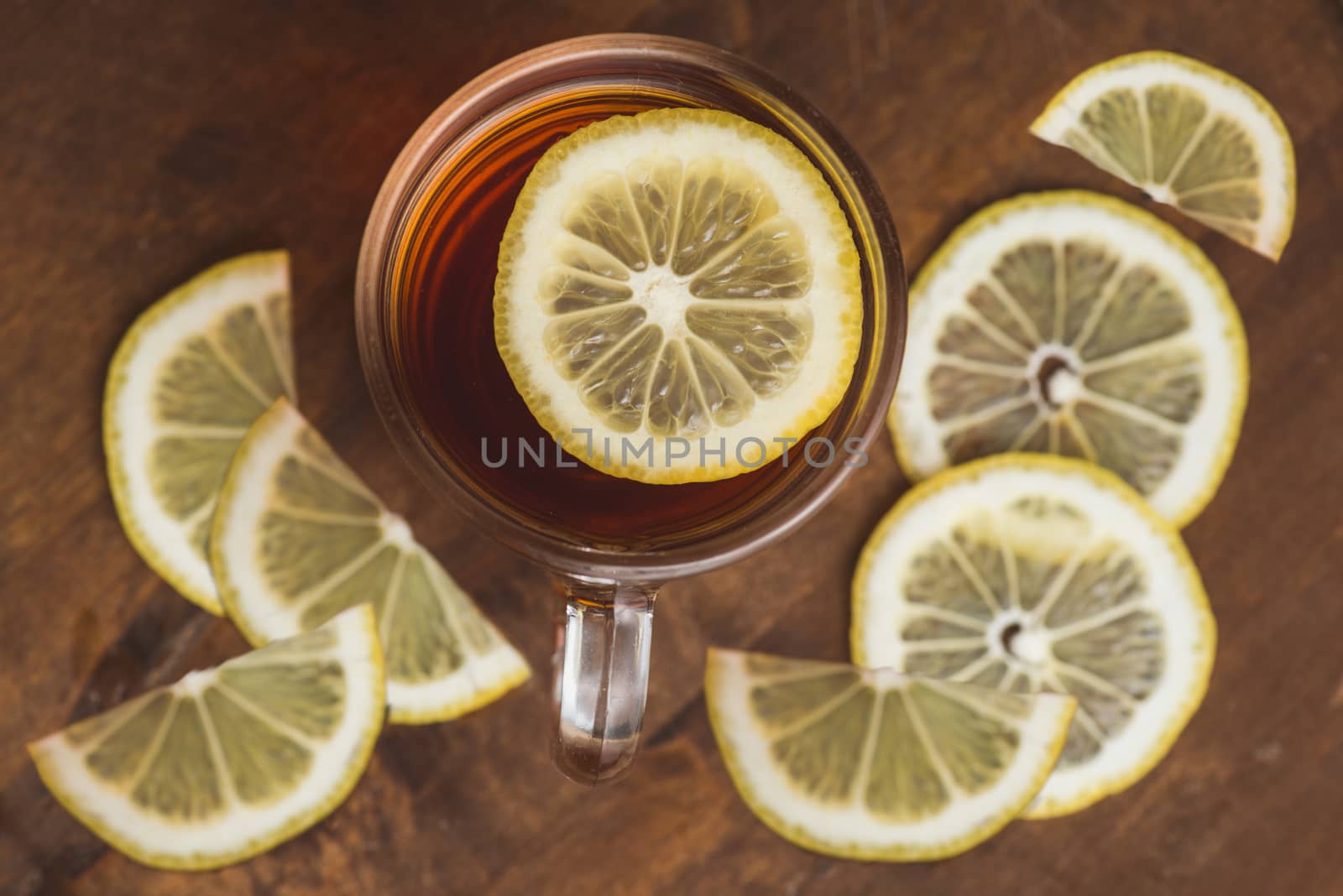 Top view of black tea with lemon in cup and on wooden plank table.