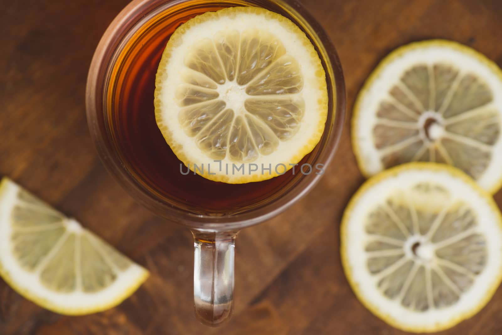 Top view of black tea with lemon in cup and on wooden plank table.