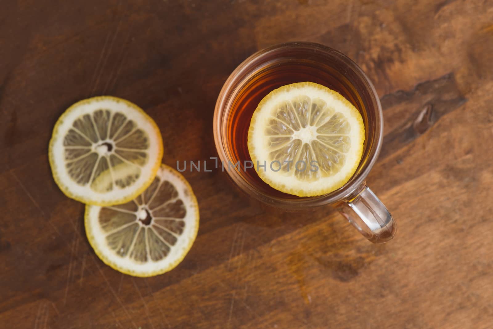 Top view of black tea with lemon in cup and on wooden plank table.