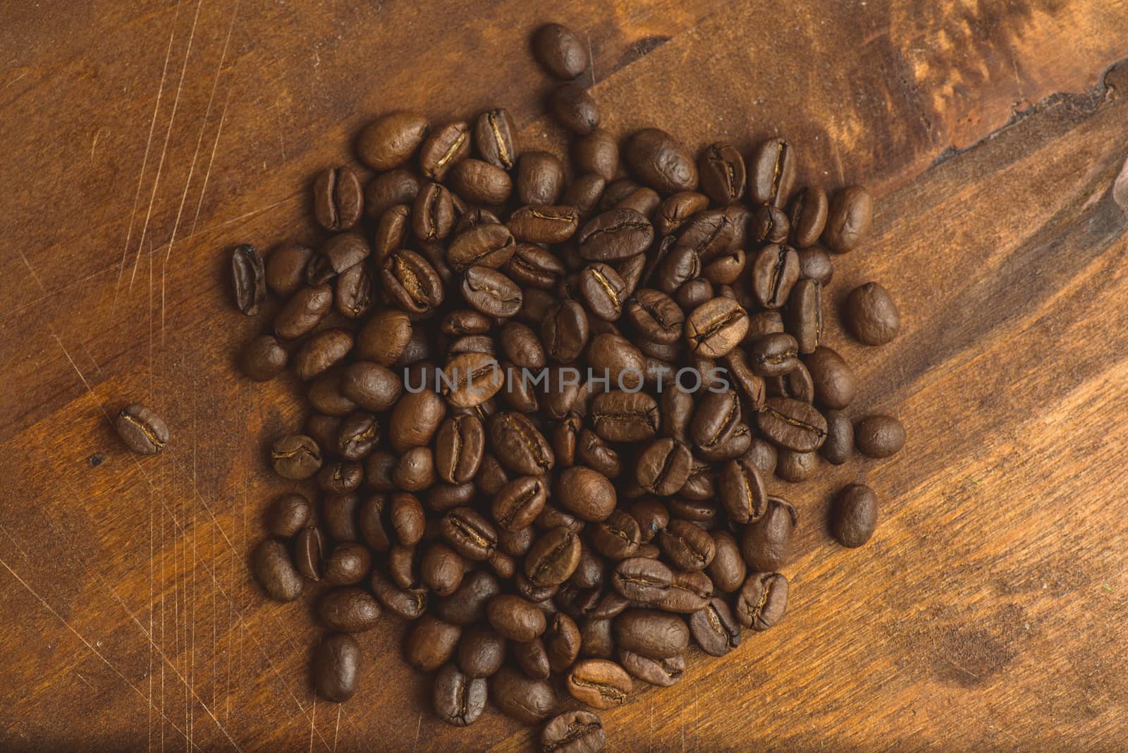 Brown coffee beans in circle shape, closeup of macro coffee beans for background and texture. On brown wooden board with magnify glass. Copyspace by skrotov