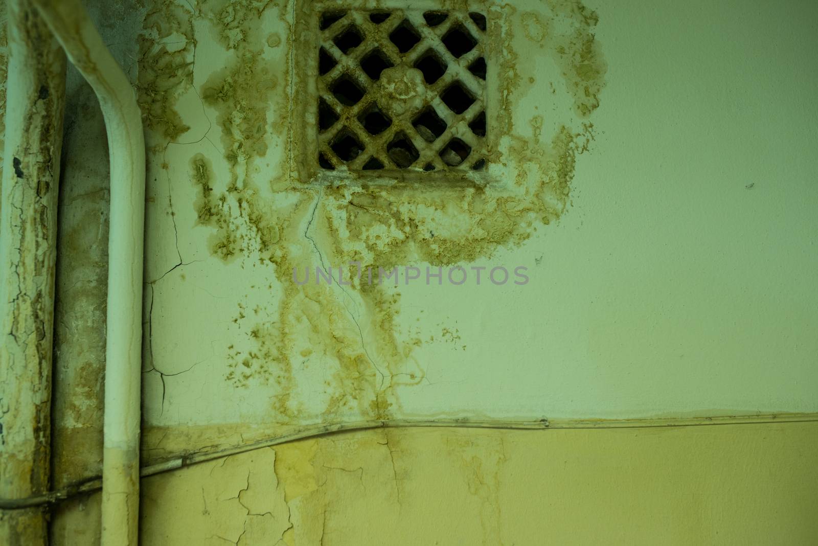 old ventilating lattice and two pipes on the wall with dirty streaked by skrotov