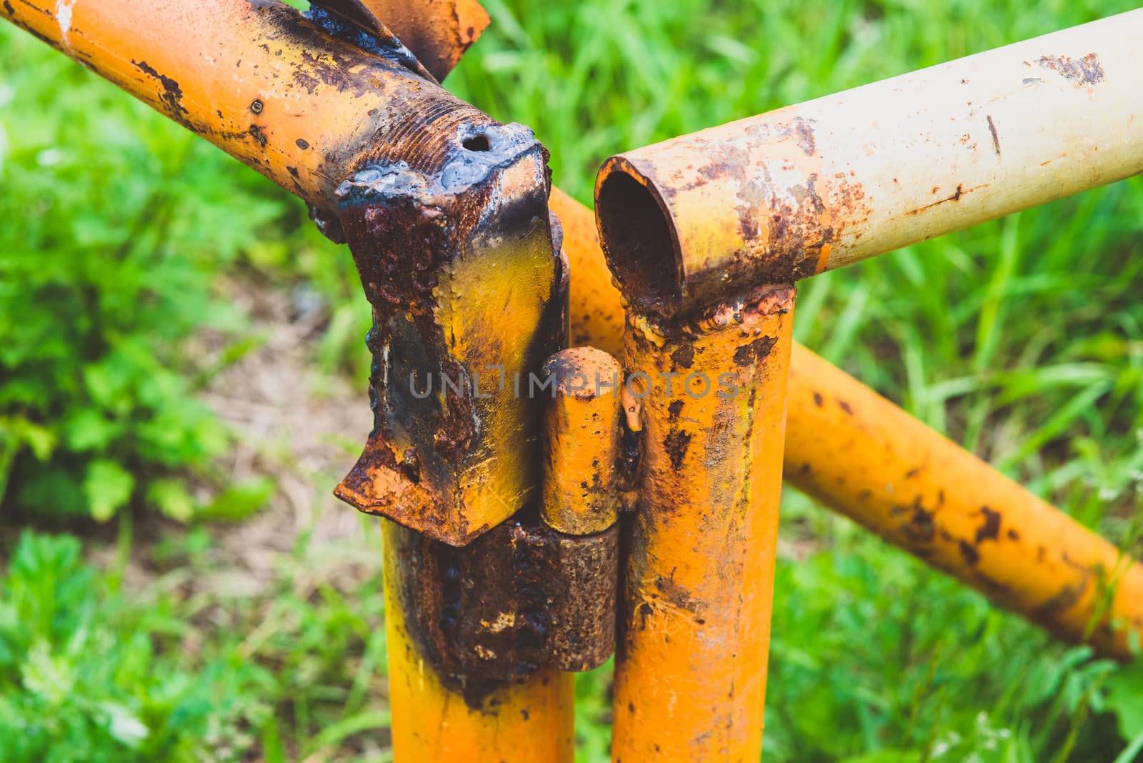 old rusty yellow pipe on a background of green grass by skrotov